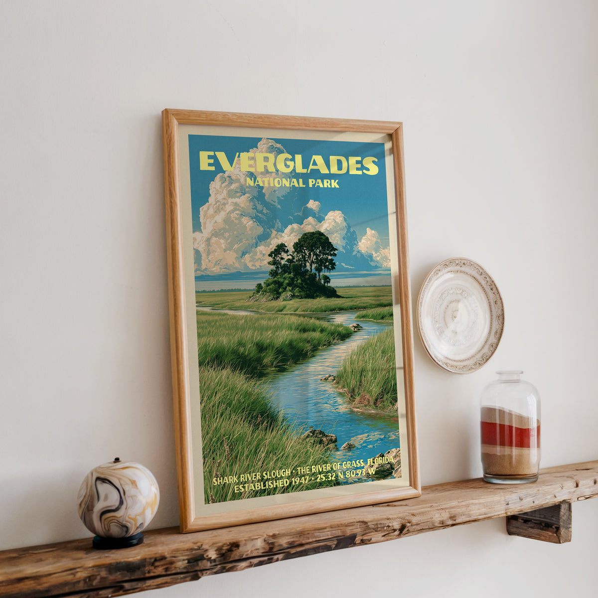 Everglades Shark River Slough print in oak, leaning on a reclaimed wood ledge with a stone sphere and sand jar