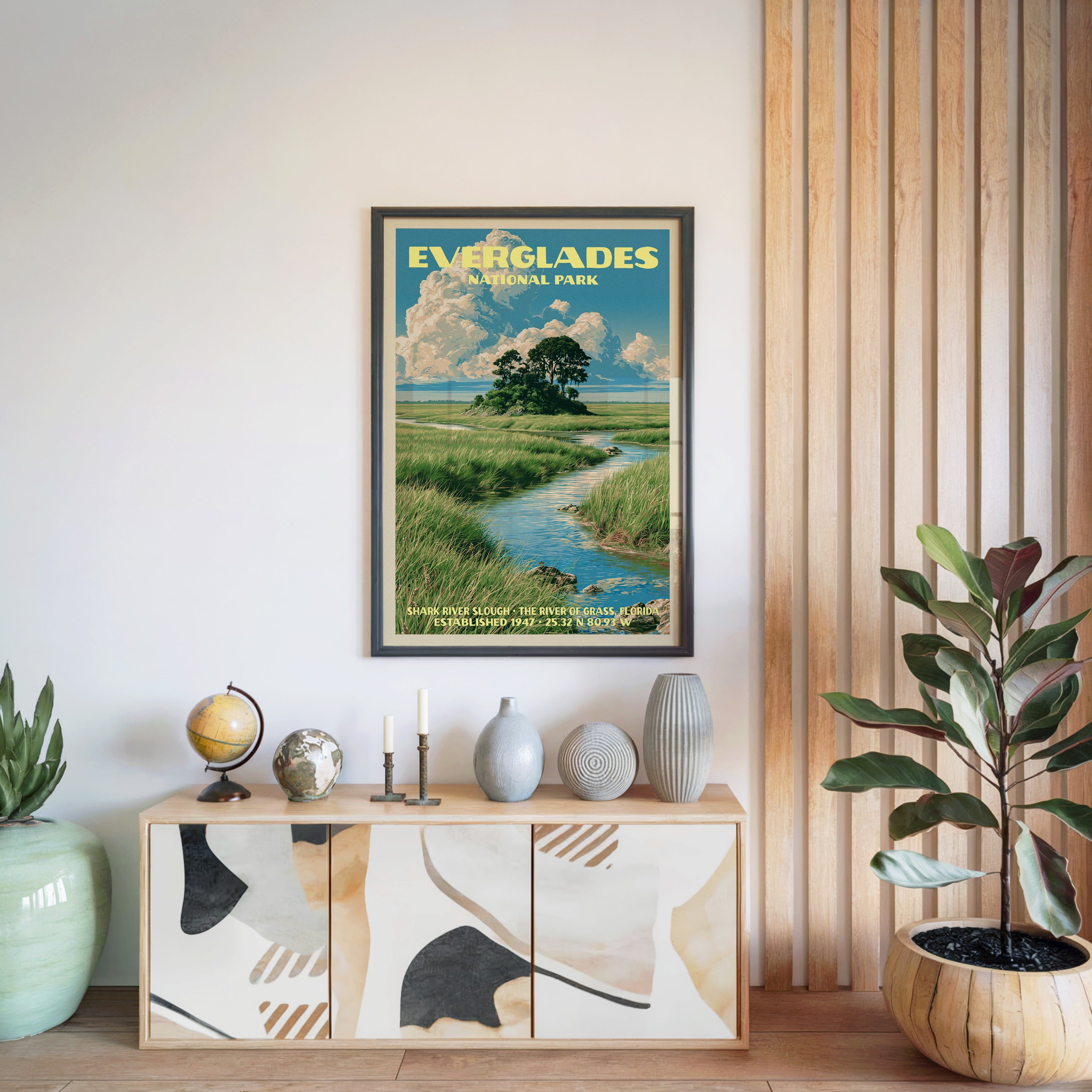 Everglades National Park poster in a black frame above a light wood sideboard beside a slatted wall panel