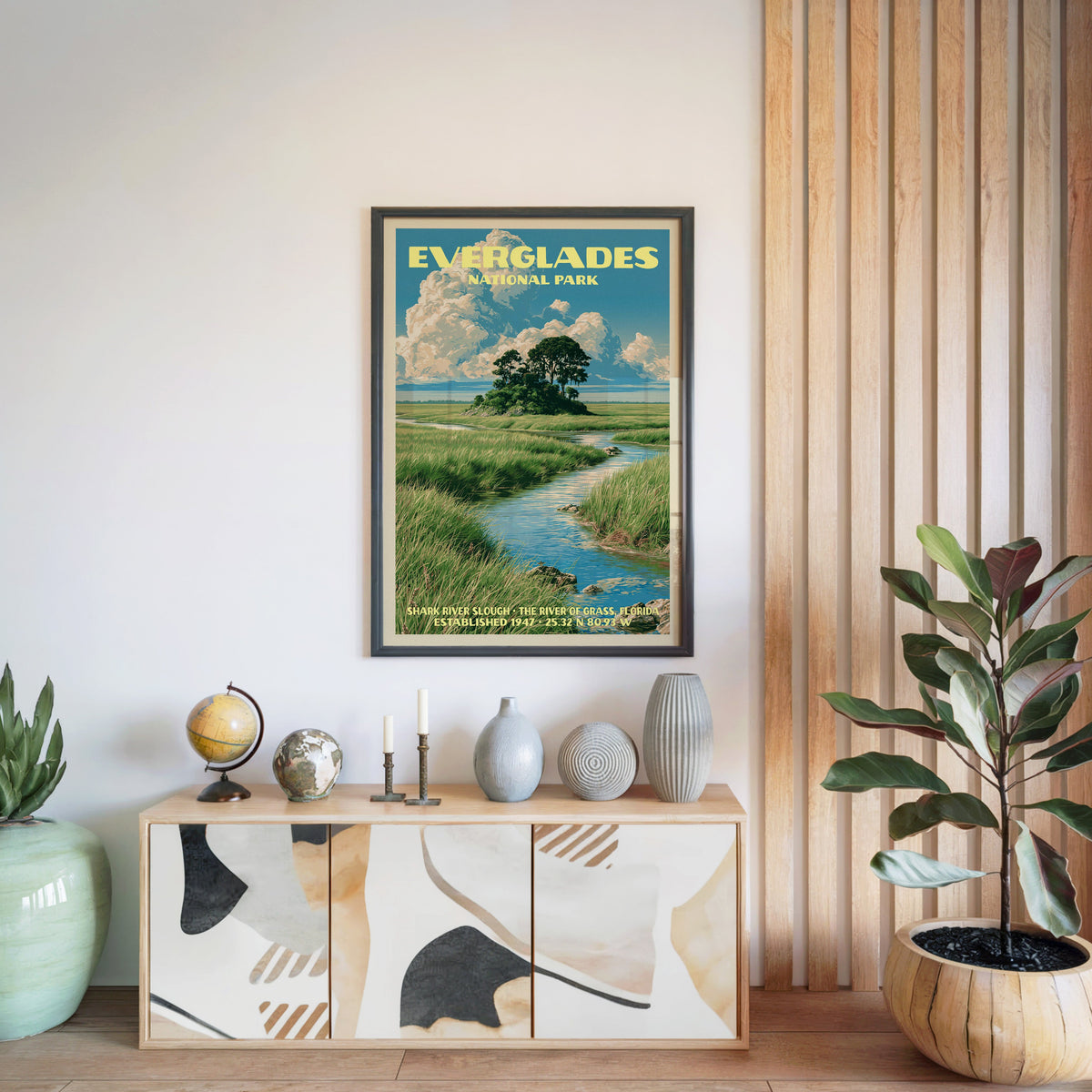Everglades National Park poster in a black frame above a light wood sideboard beside a slatted wall panel