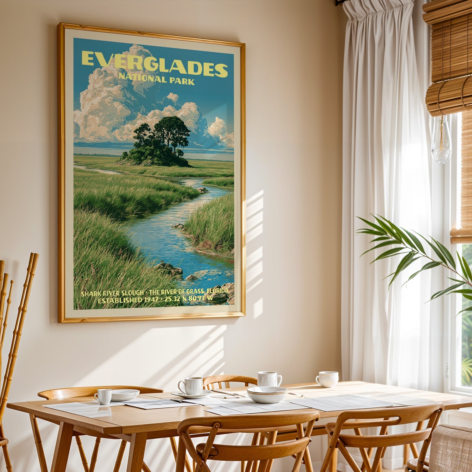 Everglades National Park print in gold above a light oak dining table by a sheer-curtained window