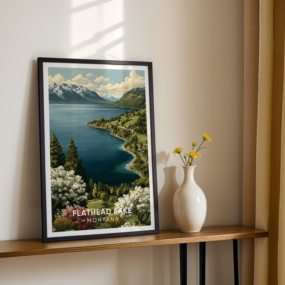 Flathead Lake canvas print in a black frame on a slim console beside yellow flowers in a vase
