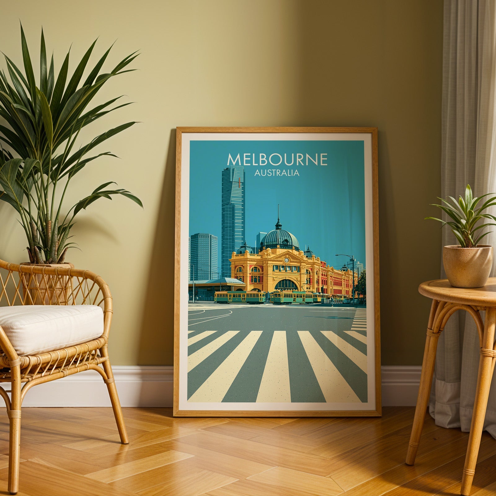 Ochre station poster in an oak frame on herringbone parquet, olive wall, rattan chair and small rattan table
