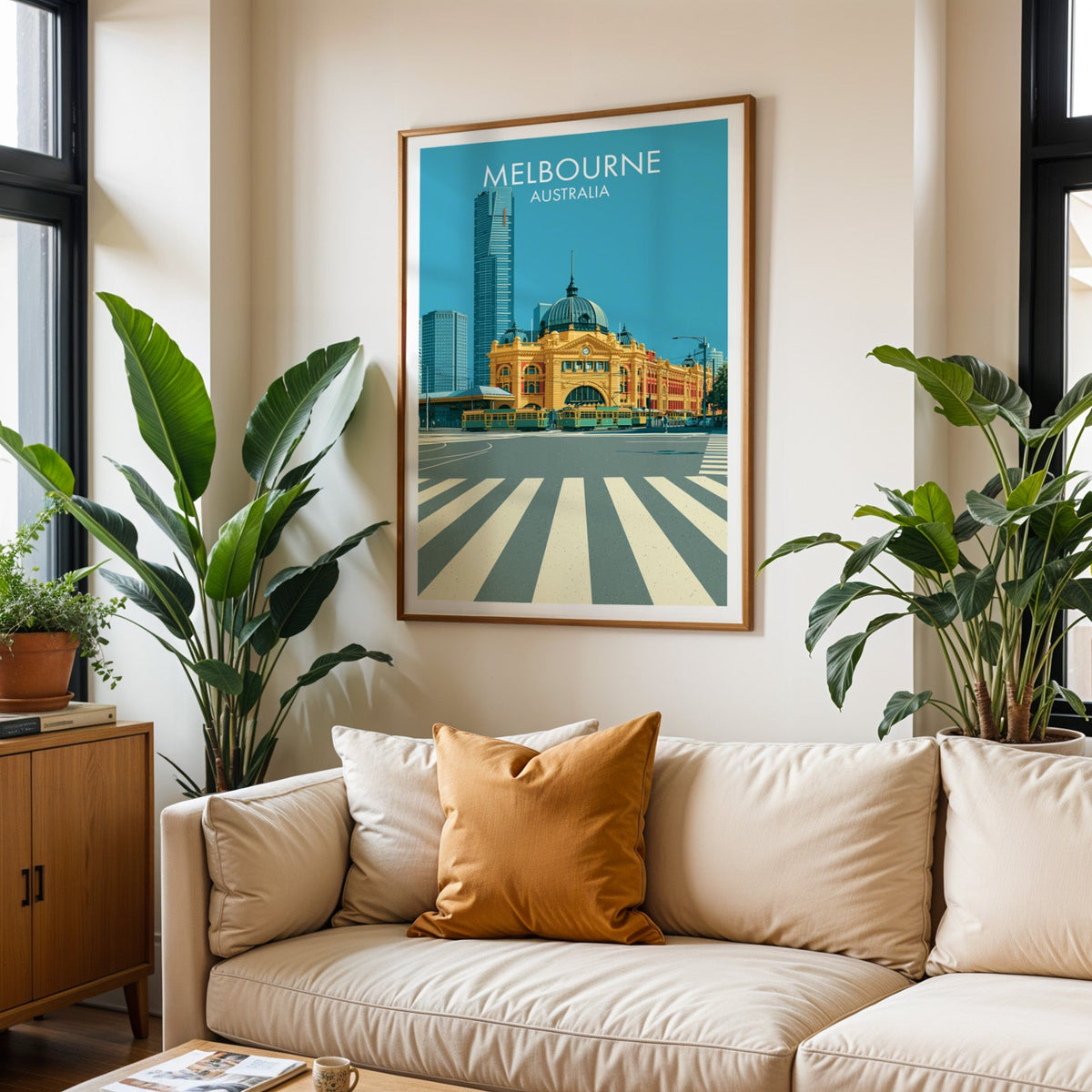 Flinders Street travel poster in an oak frame above a cream sofa with a burnt orange cushion and tall plants
