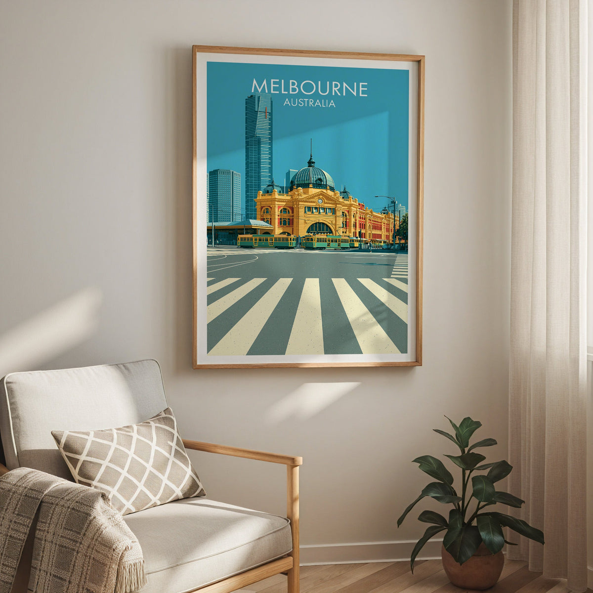 Flinders Street print in an oak frame above a cream armchair with sheer curtain and a rubber plant