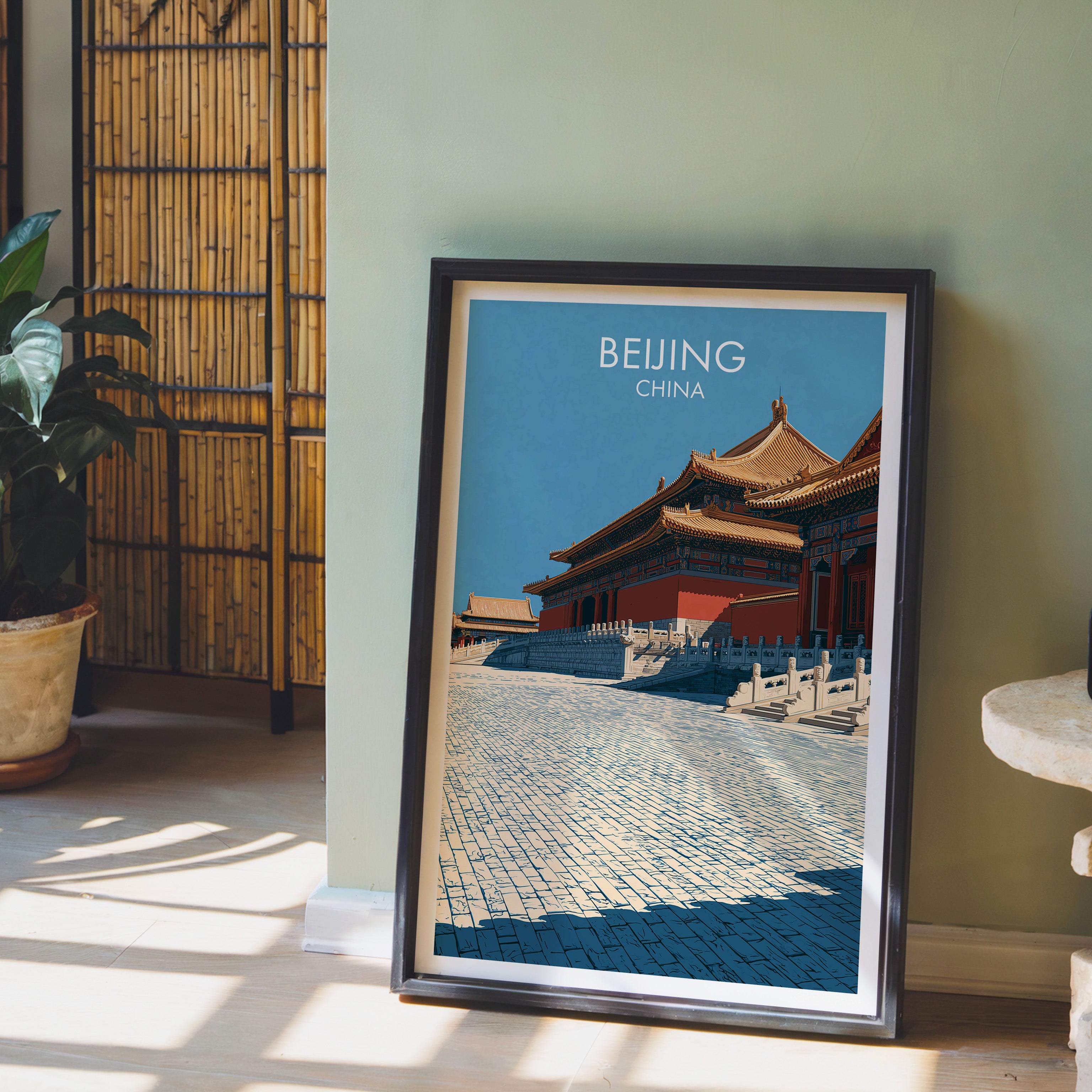 Forbidden City Beijing China wall art in a black frame leaning against a sage green wall beside a bamboo screen