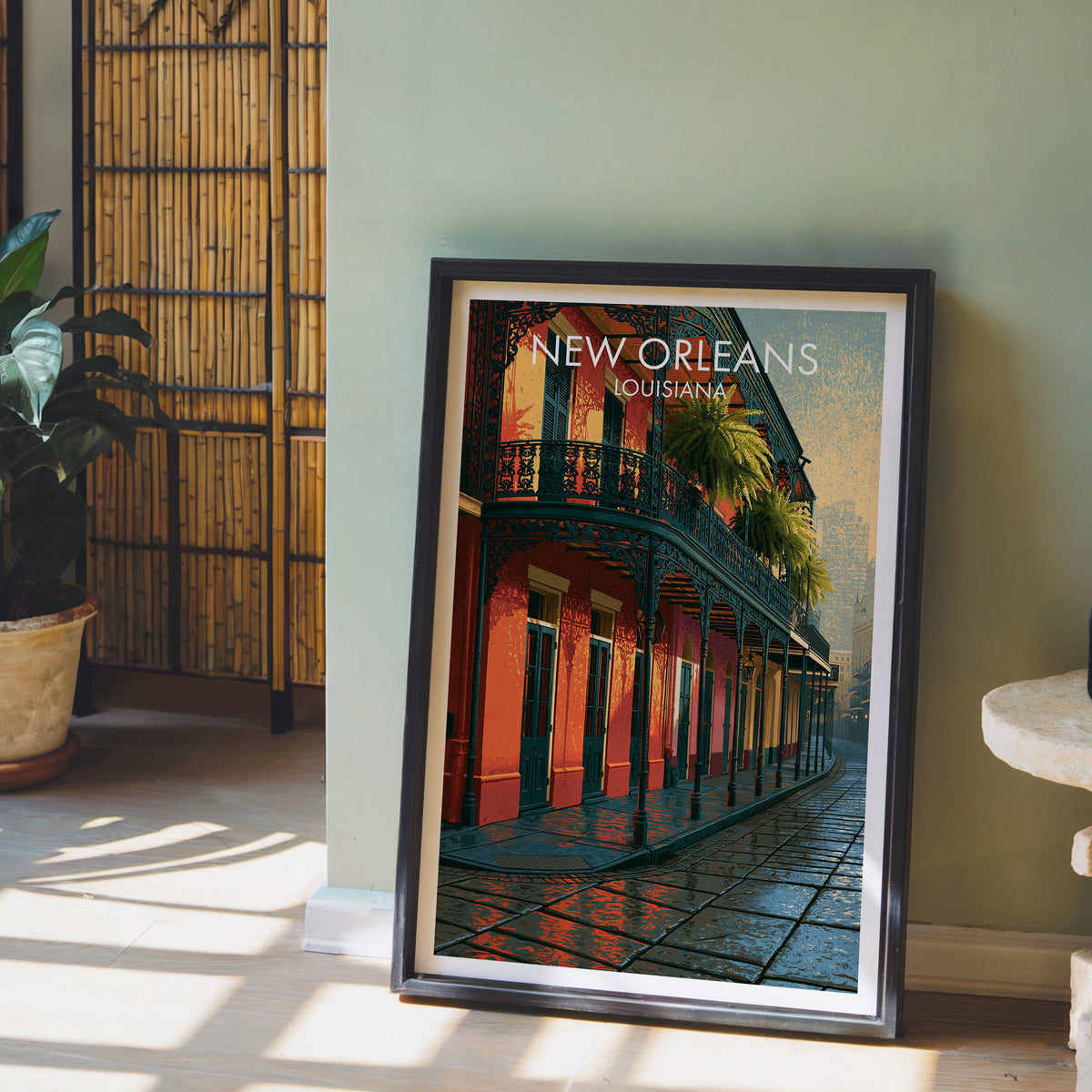 New Orleans balcony print in a black frame on a sage wall with a bamboo screen and potted orchid.