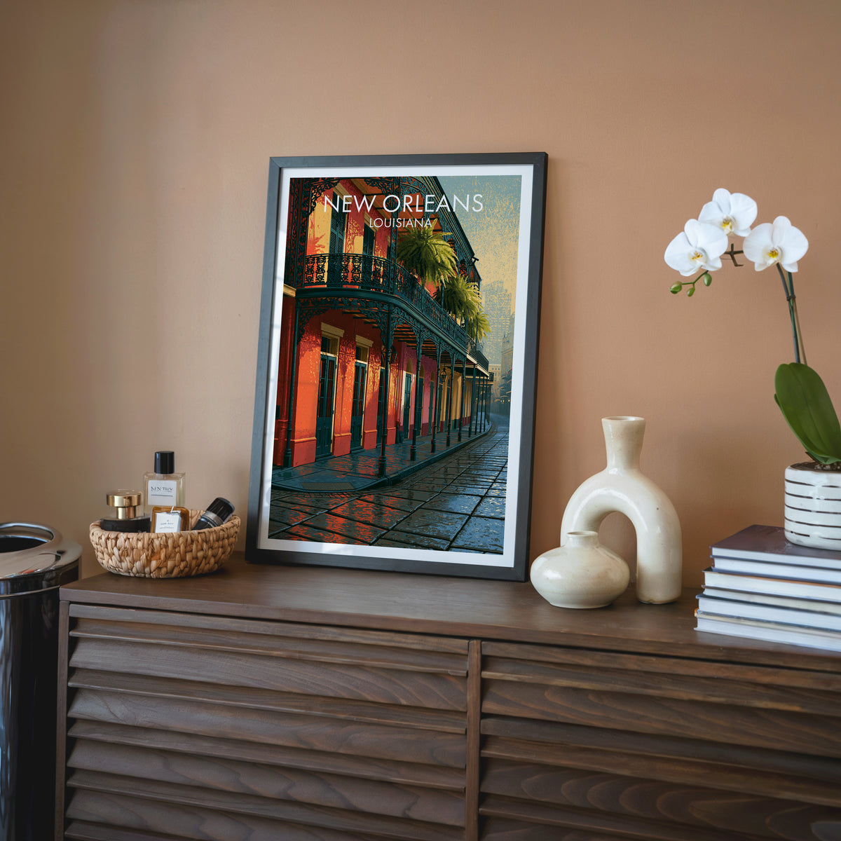 French Quarter wall art in a black frame on a walnut sideboard beside a cream vase and rattan tray.