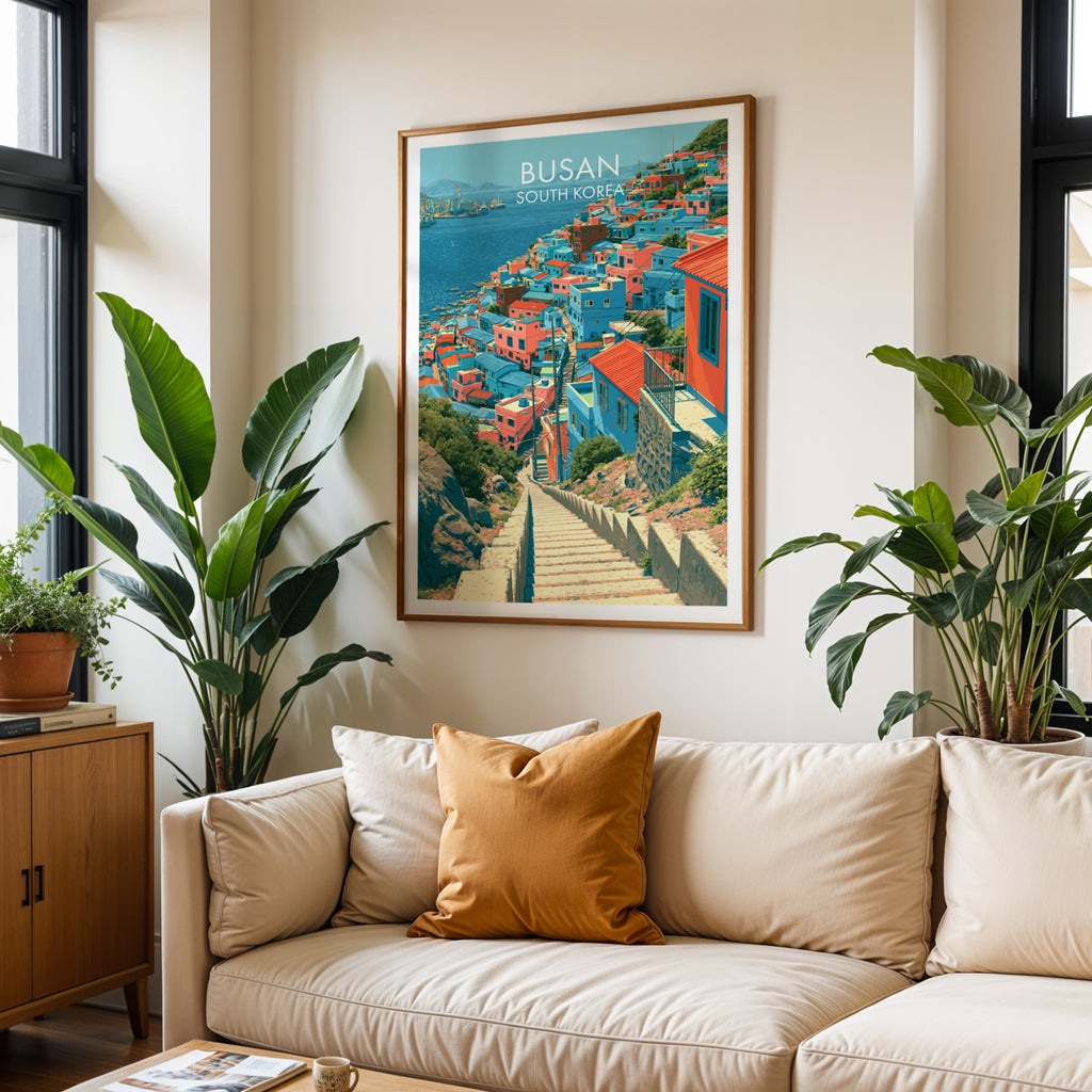 Framed Gamcheon Culture Village Busan wall art hanging above a cream sofa in a bright living room with tropical plants