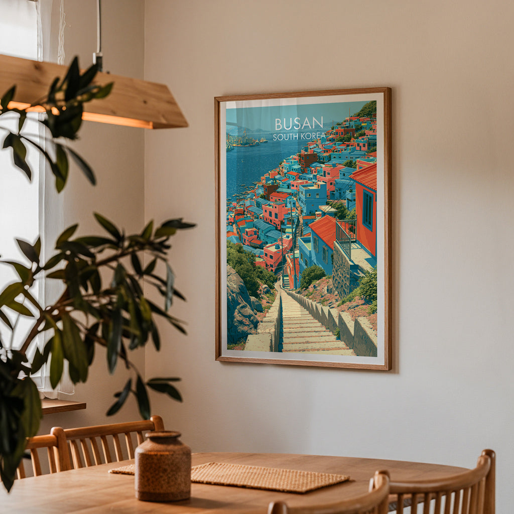 Framed Gamcheon Culture Village Busan print on a dining room wall above an oak table in warm afternoon light