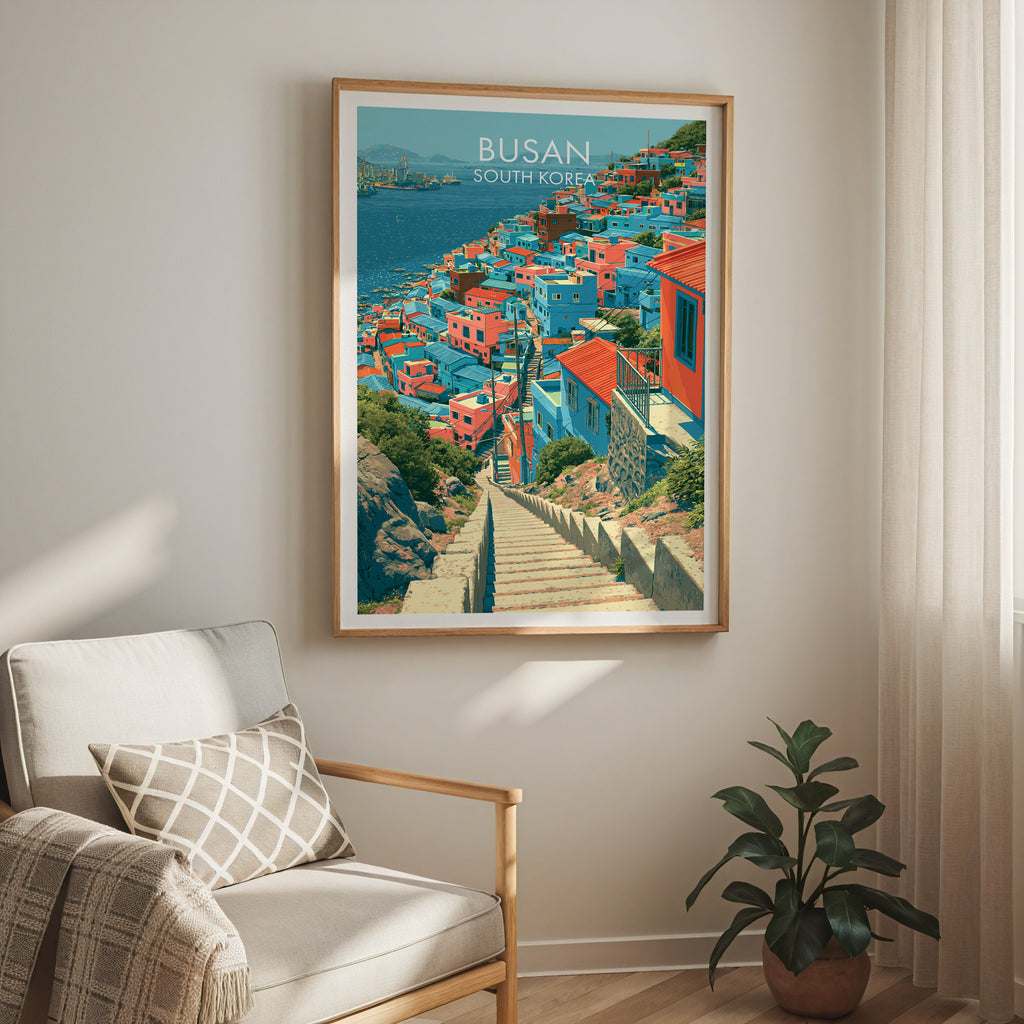 Gamcheon Culture Village Busan travel print in a light oak frame on a living room wall beside a linen armchair