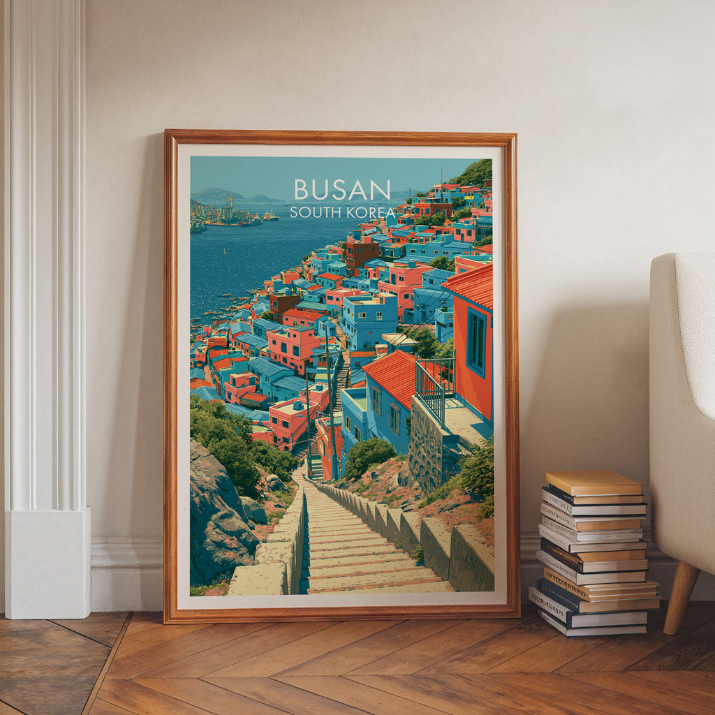 Gamcheon Culture Village Busan art print in a walnut frame leaning in a hallway beside stacked books