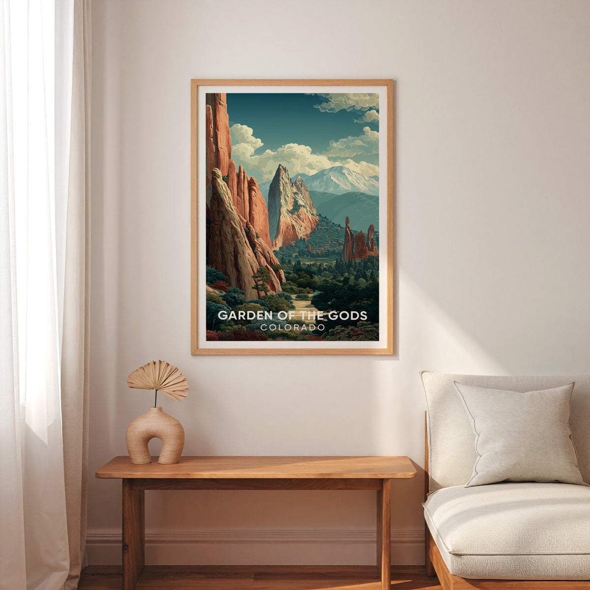 Pikes Peak view poster in oak above a narrow wood bench with a cream armchair, voile curtain and palm fan.