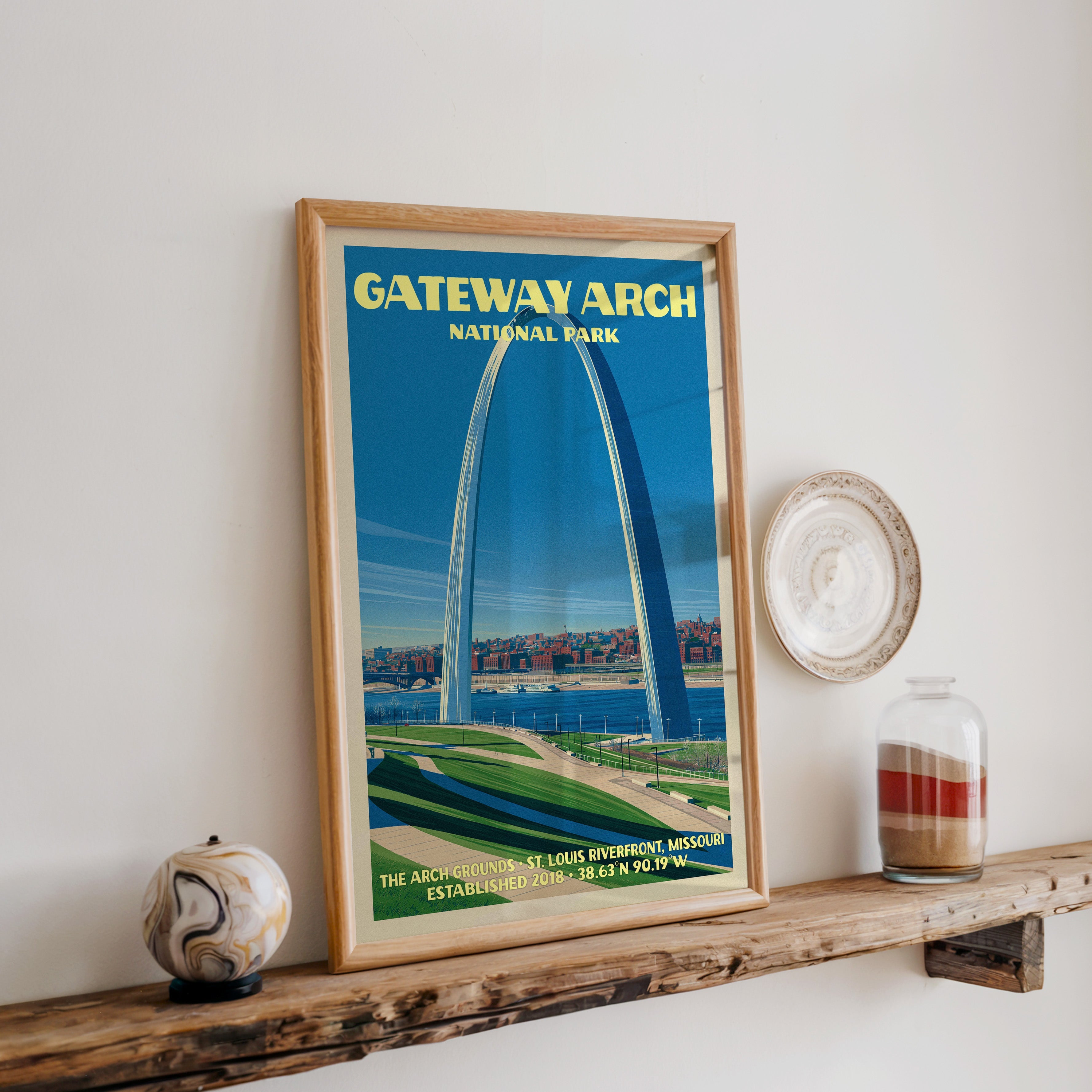 Gateway Arch print in oak, leaning on a reclaimed wood ledge with a marbled stone sphere and sand jar