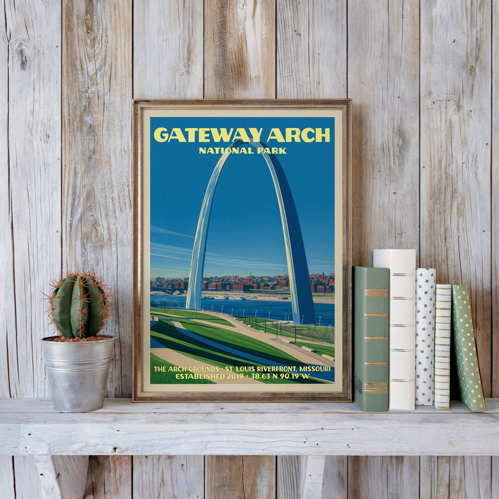 Gateway Arch vintage poster in a slim gold frame on a whitewashed plank wall beside a cactus and books