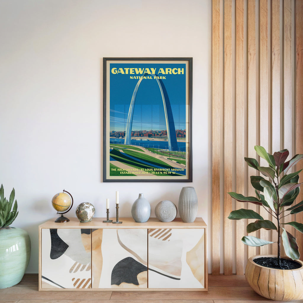 Gateway Arch National Park poster in a black frame above a light wood sideboard beside a slatted panel