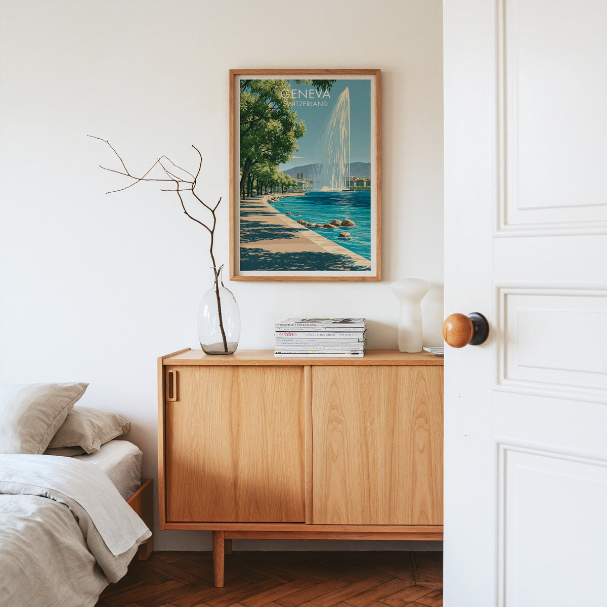 Geneva lakefront print, oak frame above a light oak sideboard with bare branches in a glass vase