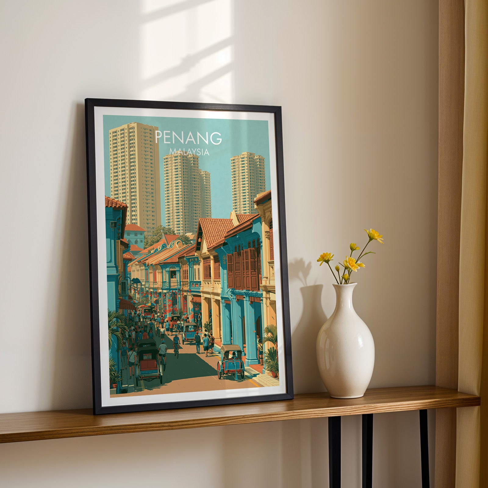 Black framed Georgetown Penang Malaysia print on a narrow hallway console in sunlight, styled with yellow flowers