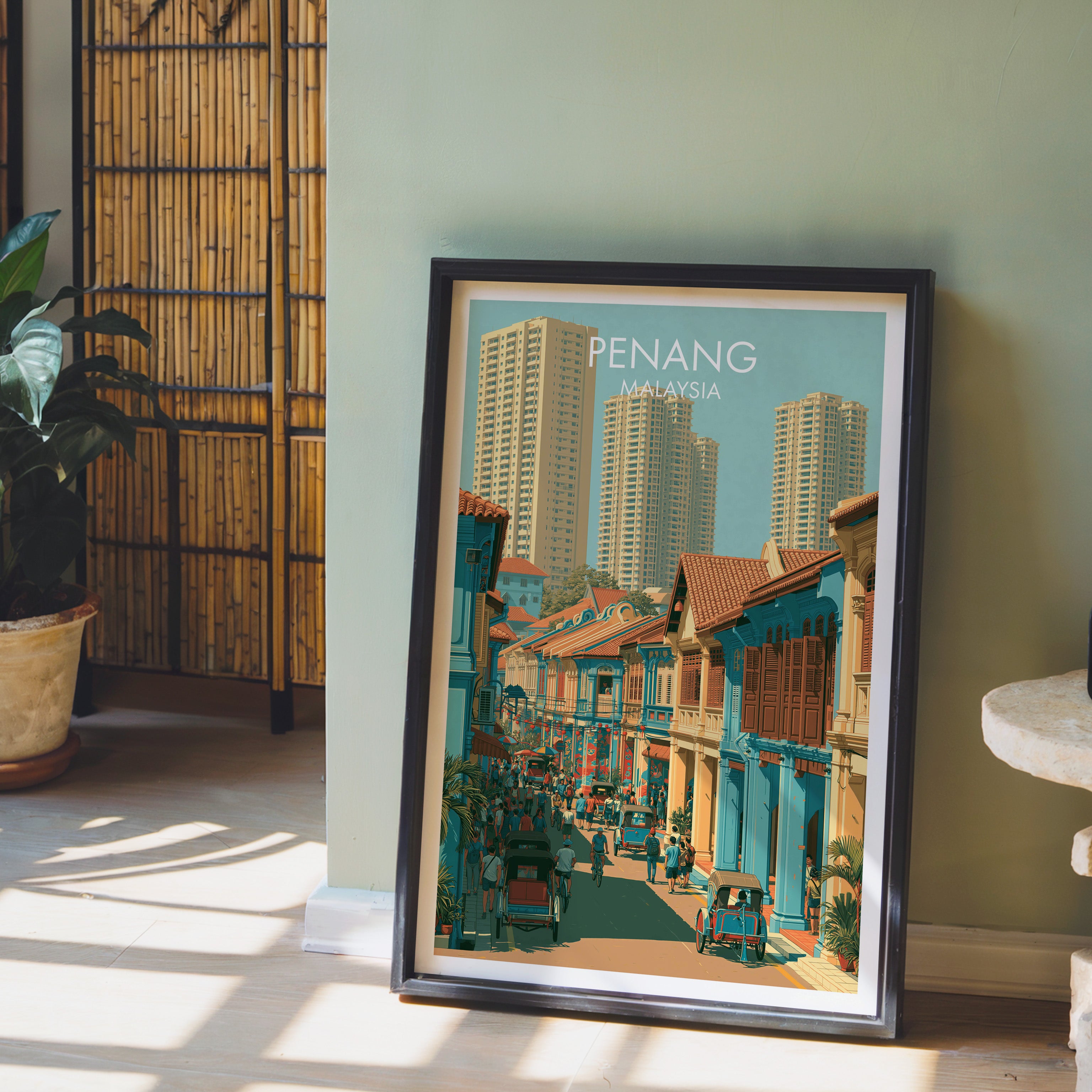 Georgetown Penang Malaysia wall art in a black frame leaning against a sage green wall beside a bamboo screen