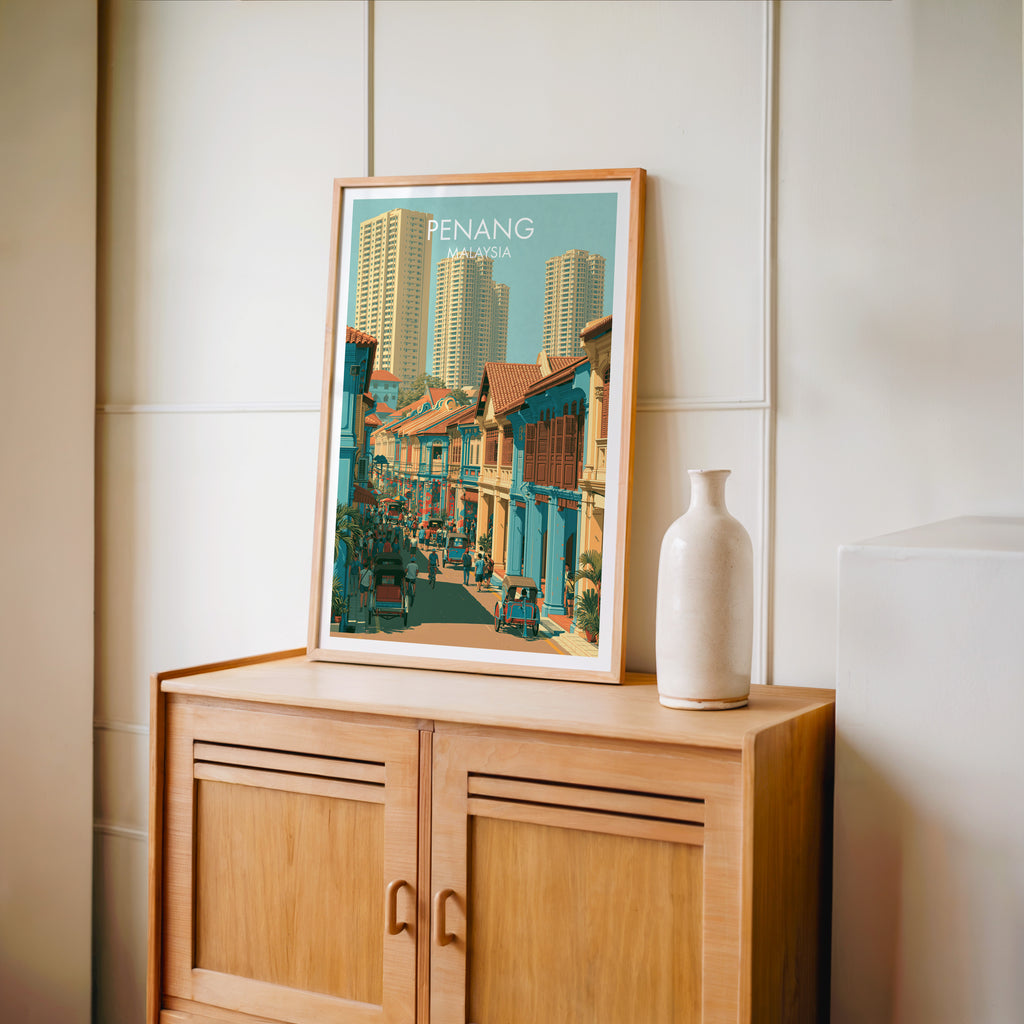 Small Georgetown Penang Malaysia travel poster in an oak frame on a mid-century sideboard with a ceramic vase