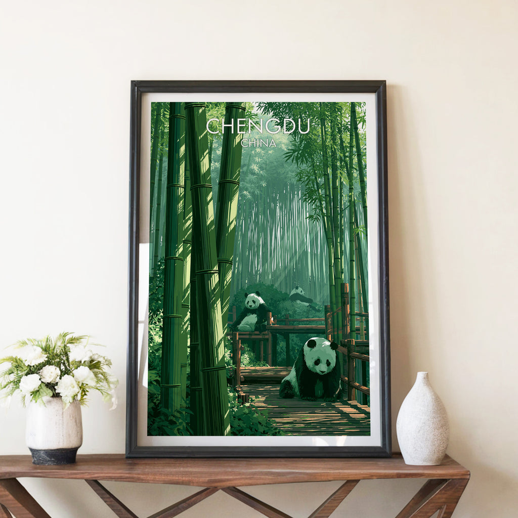 Giant Pandas Chengdu China travel poster in a black frame on a wooden console table with white flowers