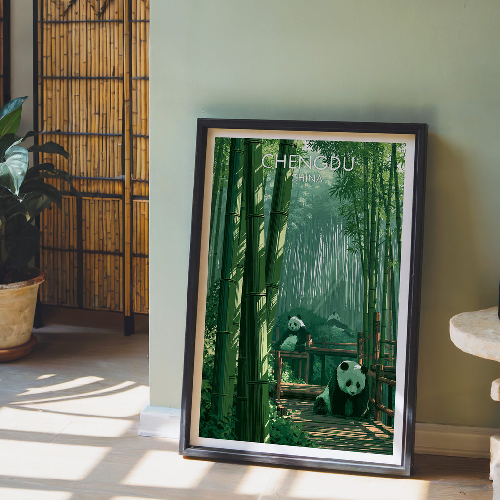 Giant Pandas Chengdu China wall art in a black frame leaning against a sage green wall beside a bamboo screen