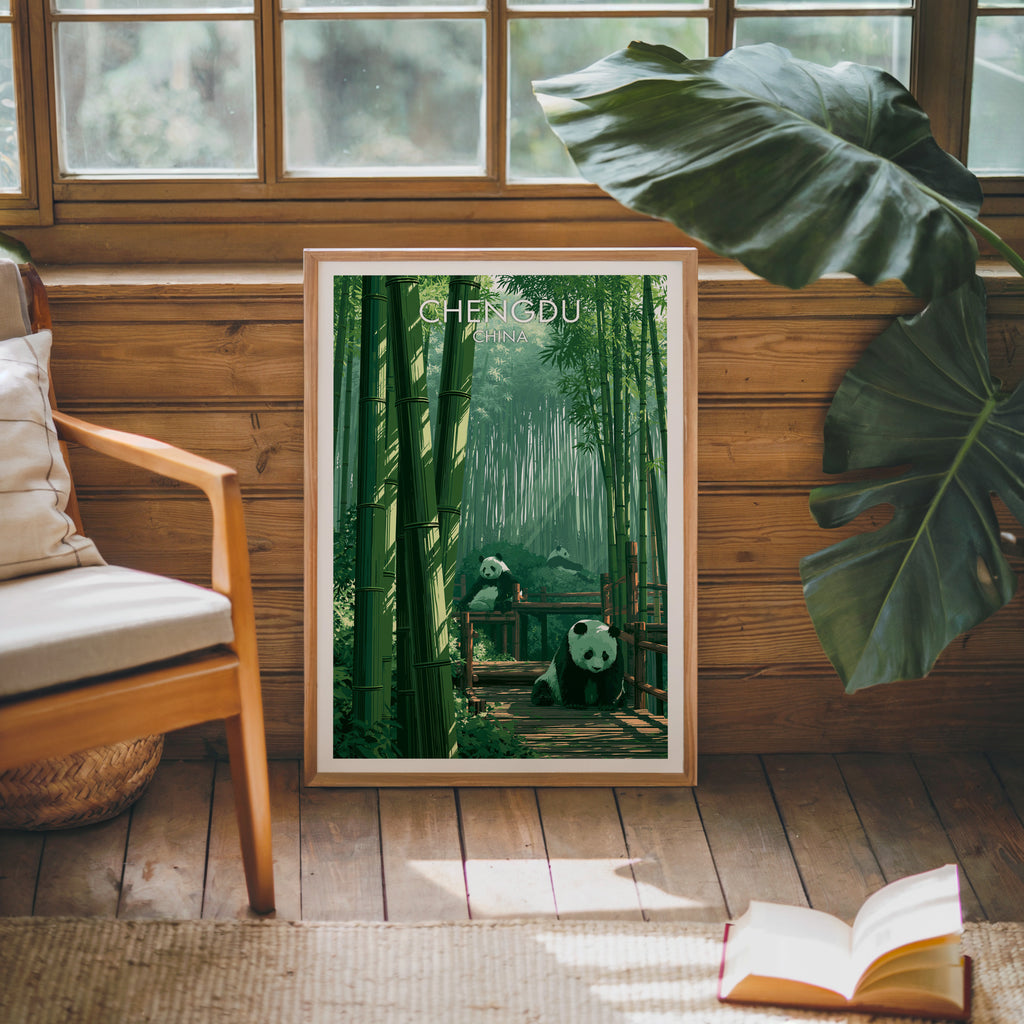 Framed Giant Pandas Chengdu China poster leaning against a timber cabin wall with monstera leaves and an open book