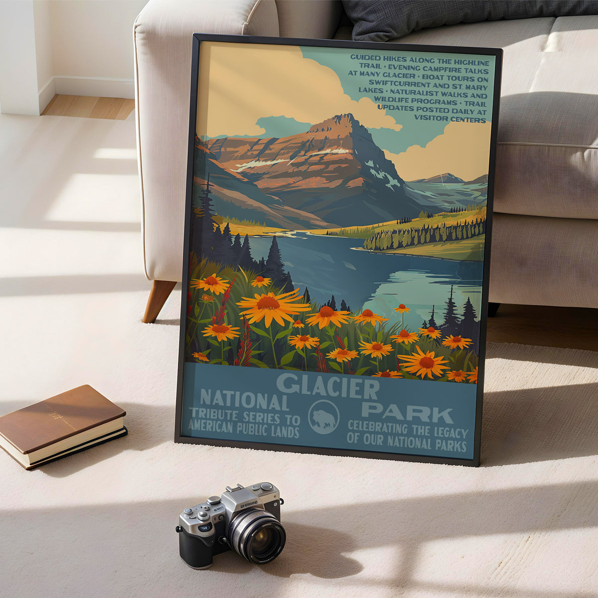 Glacier National Park poster leaning on the floor beside books and a vintage camera