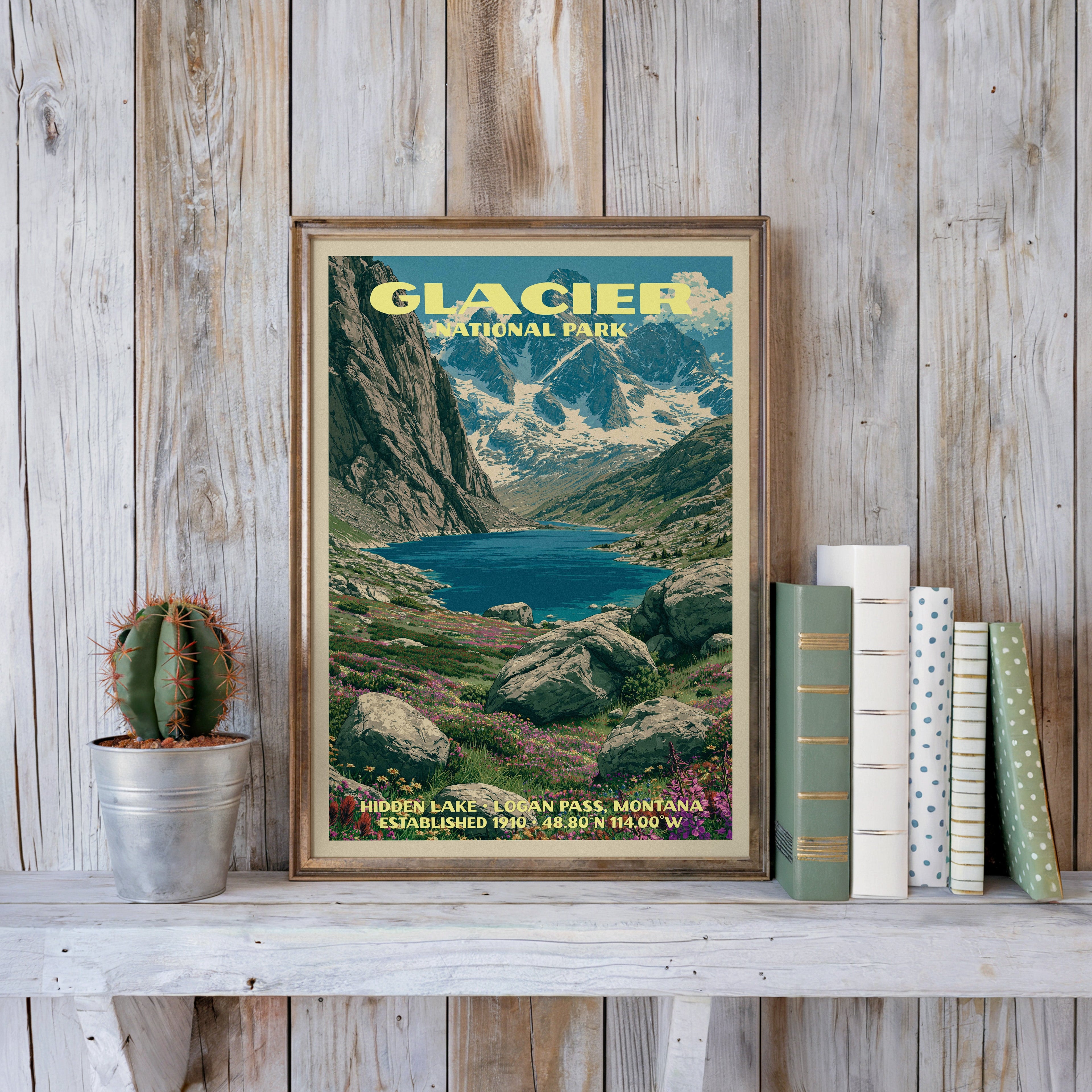 Glacier National Park vintage poster in a slim gold frame on a whitewashed plank wall with a cactus and books