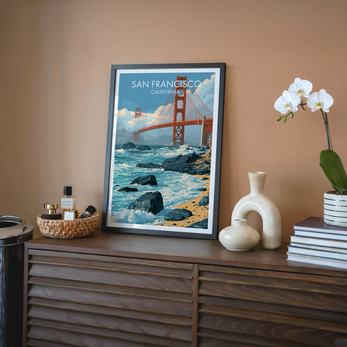Golden Gate wall art in a black frame on a walnut sideboard with a white orchid and cream vase.