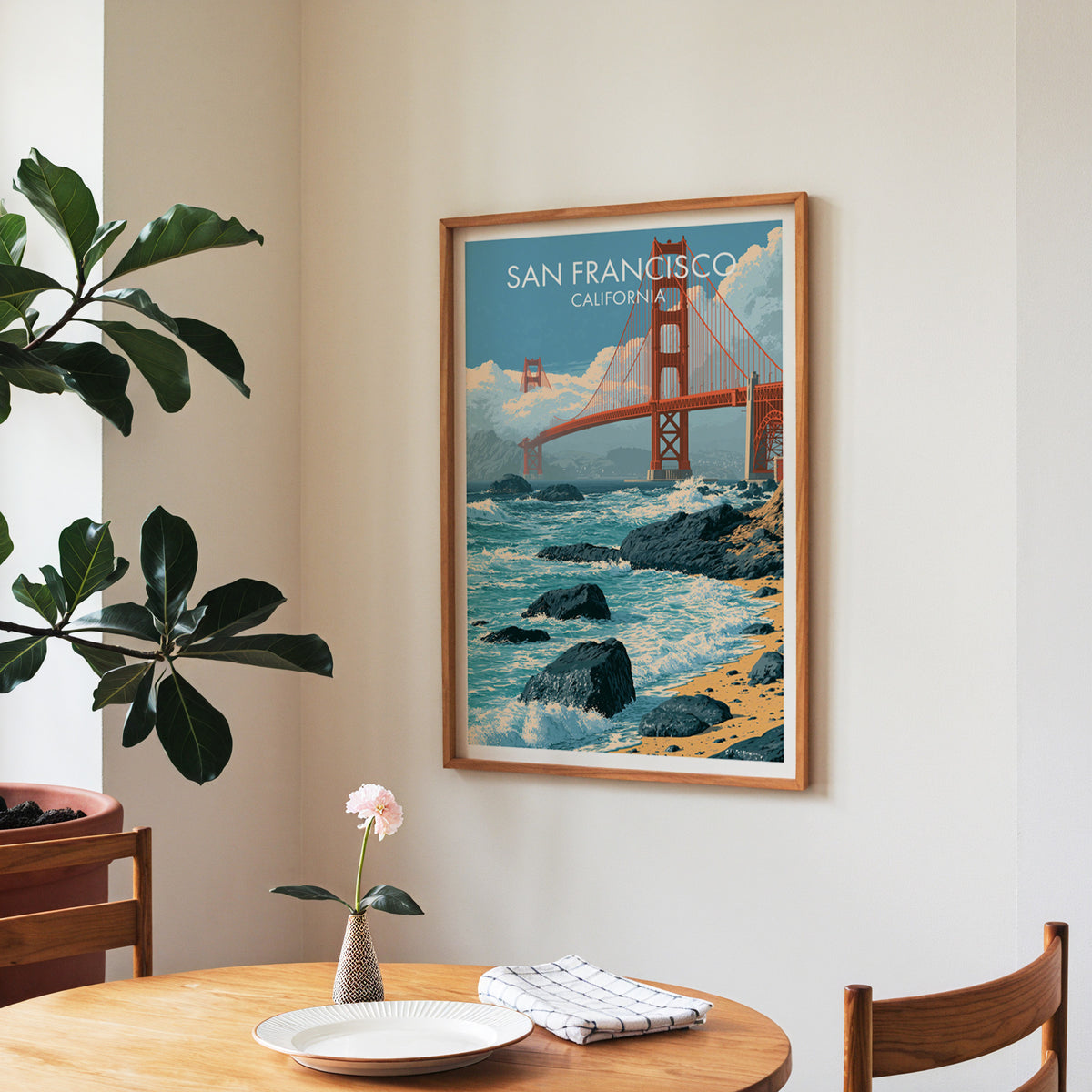Surf and bridge print in a walnut frame in a dining corner with roses and a fiddle-leaf fig.