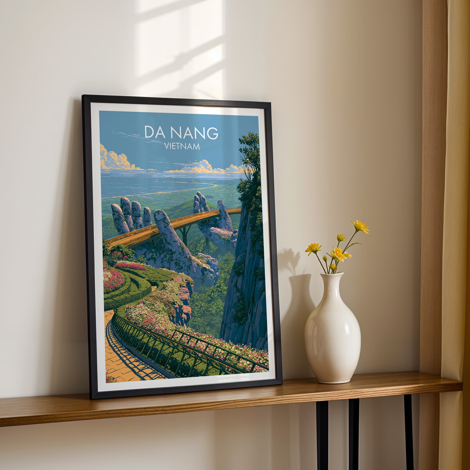 Black framed Golden Bridge Da Nang Vietnam print on a narrow hallway console in sunlight, styled with yellow flowers