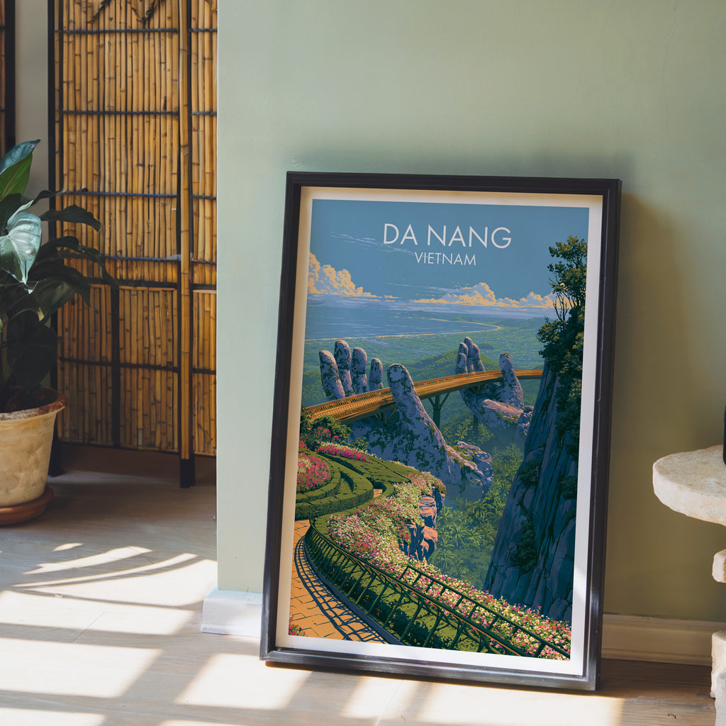 Golden Bridge Da Nang Vietnam wall art in a black frame leaning against a sage green wall beside a bamboo screen