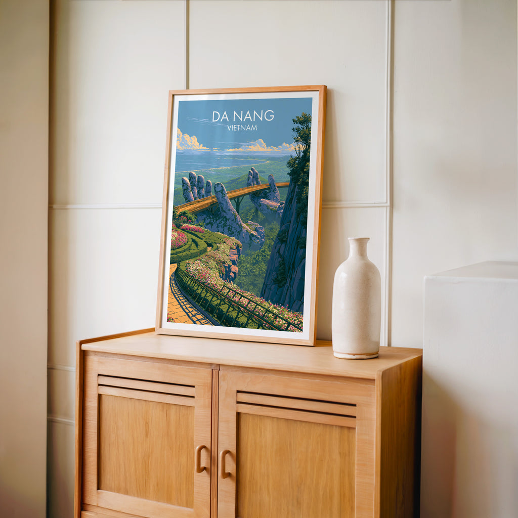 Small Golden Bridge Da Nang Vietnam travel poster in an oak frame on a mid-century sideboard with a ceramic vase