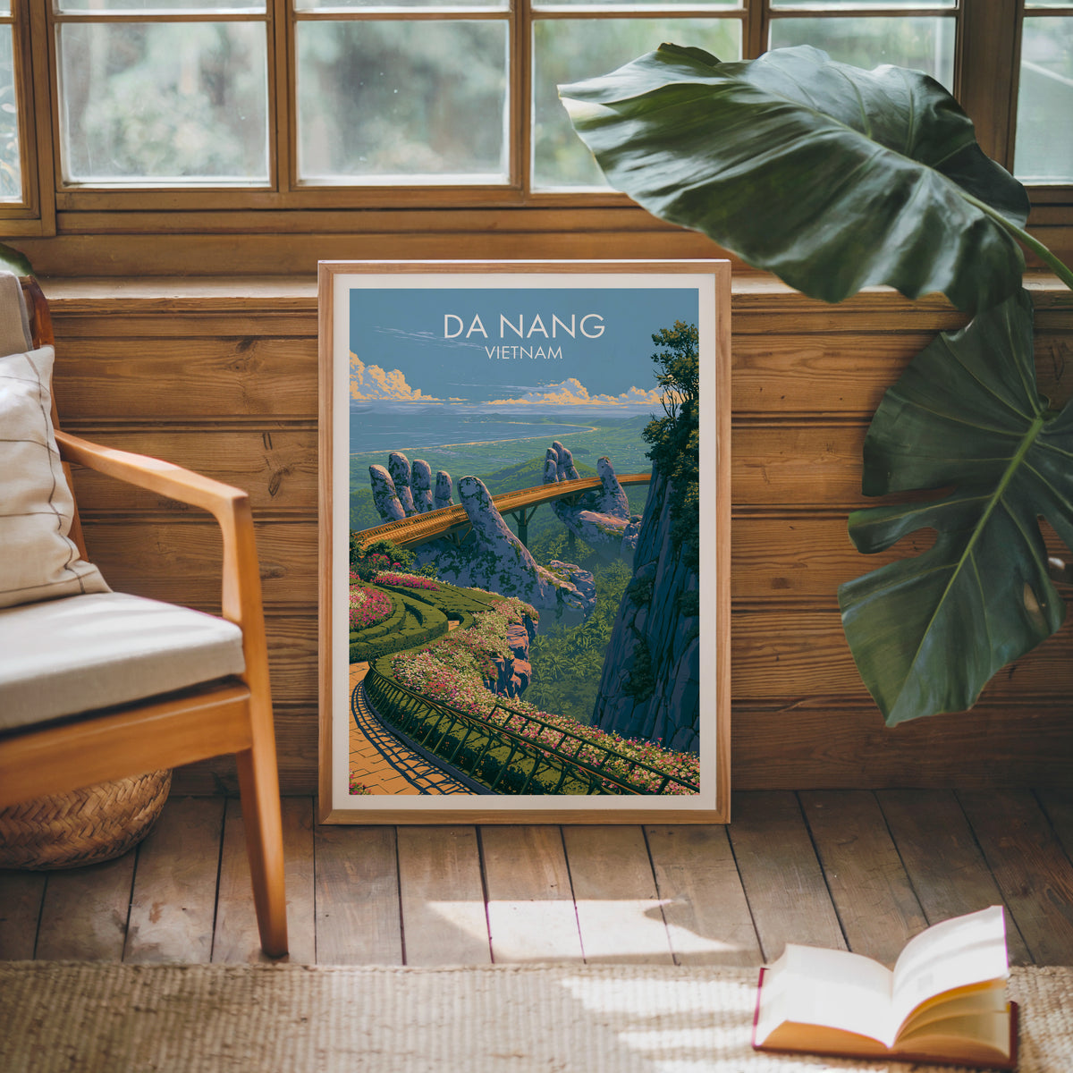 Da Nang stone hands bridge print in an oak frame leaning on a pine cabin wall with a monstera leaf and open book