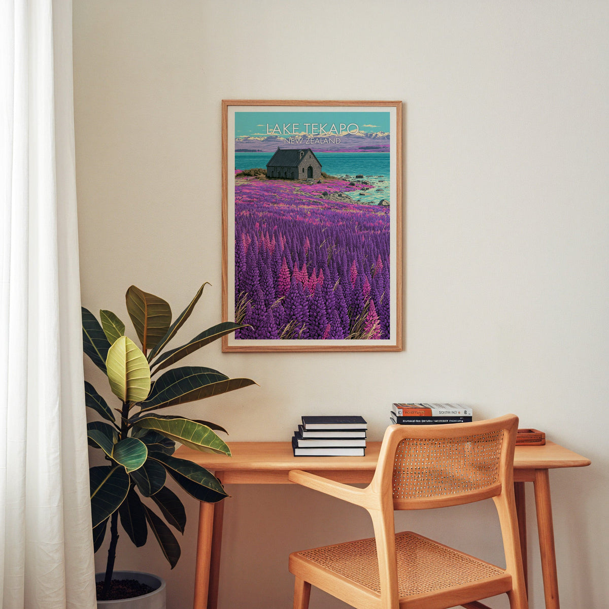 Chapel and lupin travel print in oak above a wooden desk with a cane chair and rubber plant