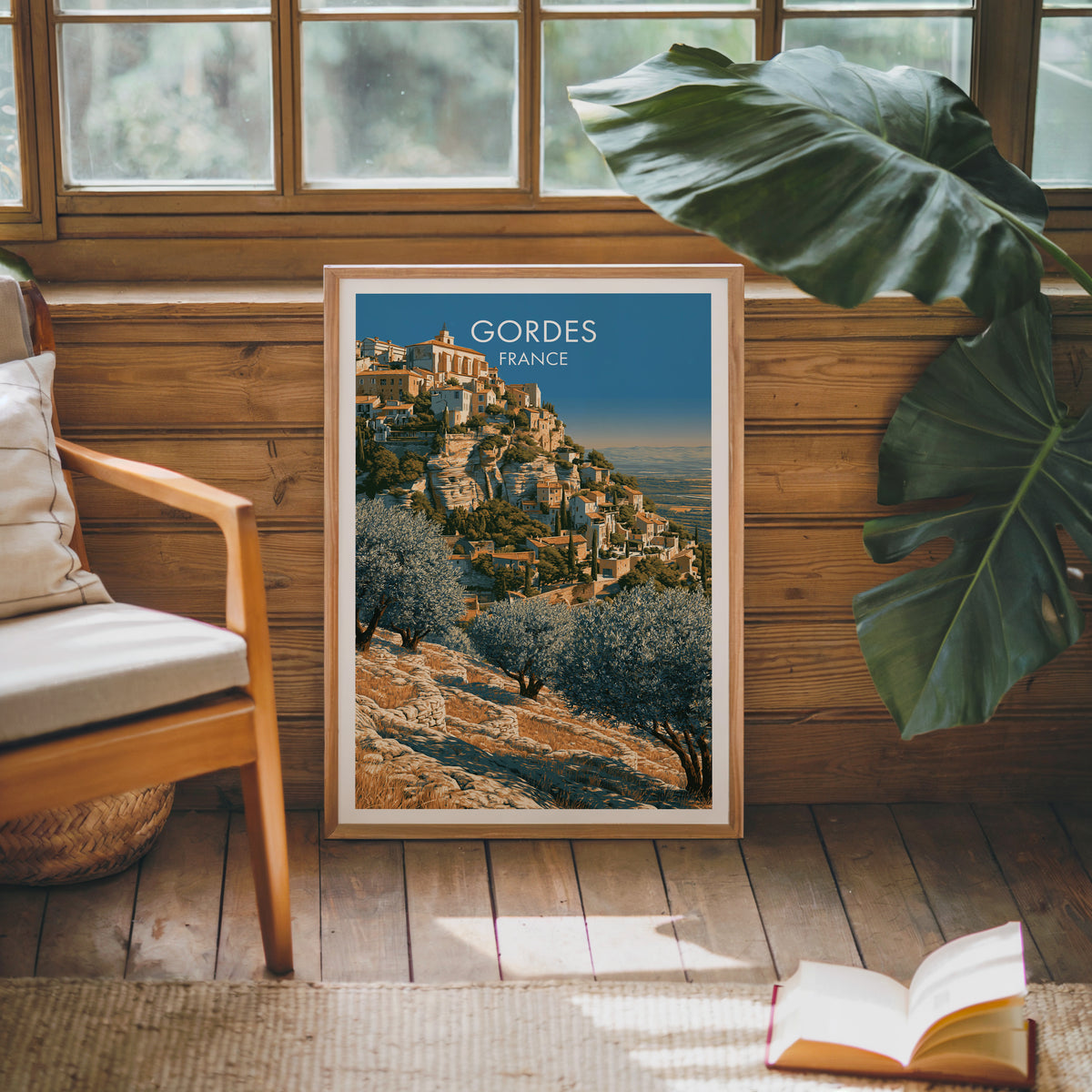 Gordes travel poster, oak frame leaning on a wood-panelled sunroom wall by a mid-century armchair