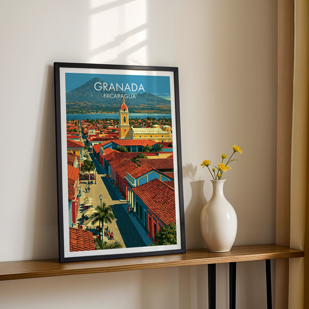 Nicaraguan rooftop view in a black frame on a narrow wood shelf, yellow daisies against a sunlit cream wall