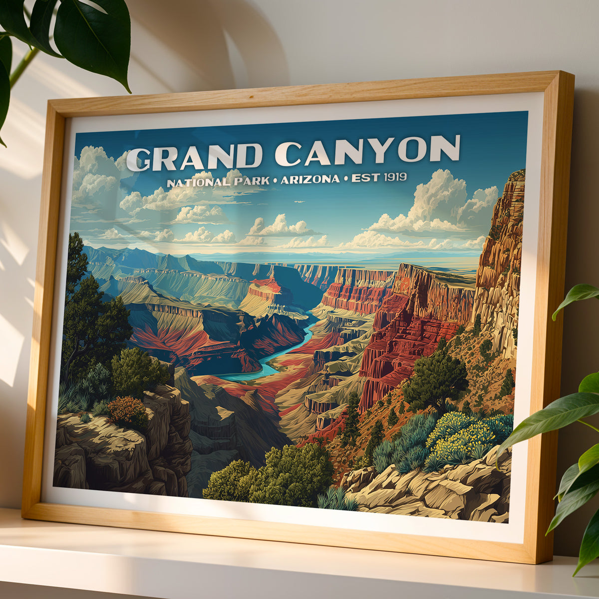 Grand Canyon National Park wall art print in a light oak frame, leaning on a white shelf in warm sunlight beside a monstera plant