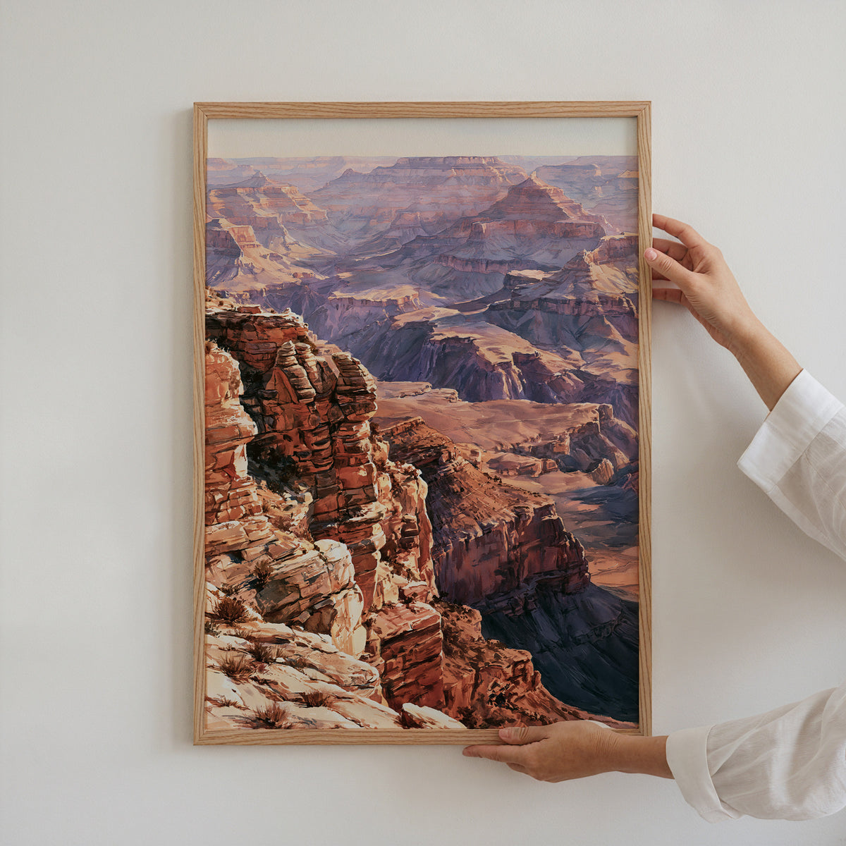 Hands holding an oak-framed Grand Canyon National Park watercolor art print against a plain white wall