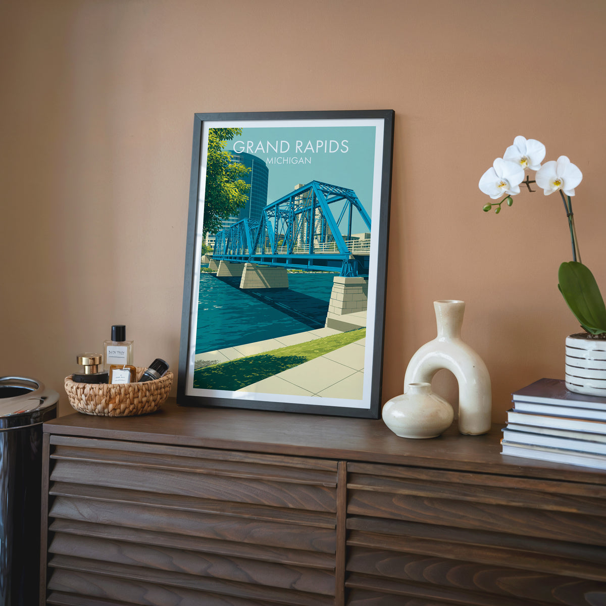 Steel truss bridge wall art in a black frame on a walnut sideboard by a terracotta wall