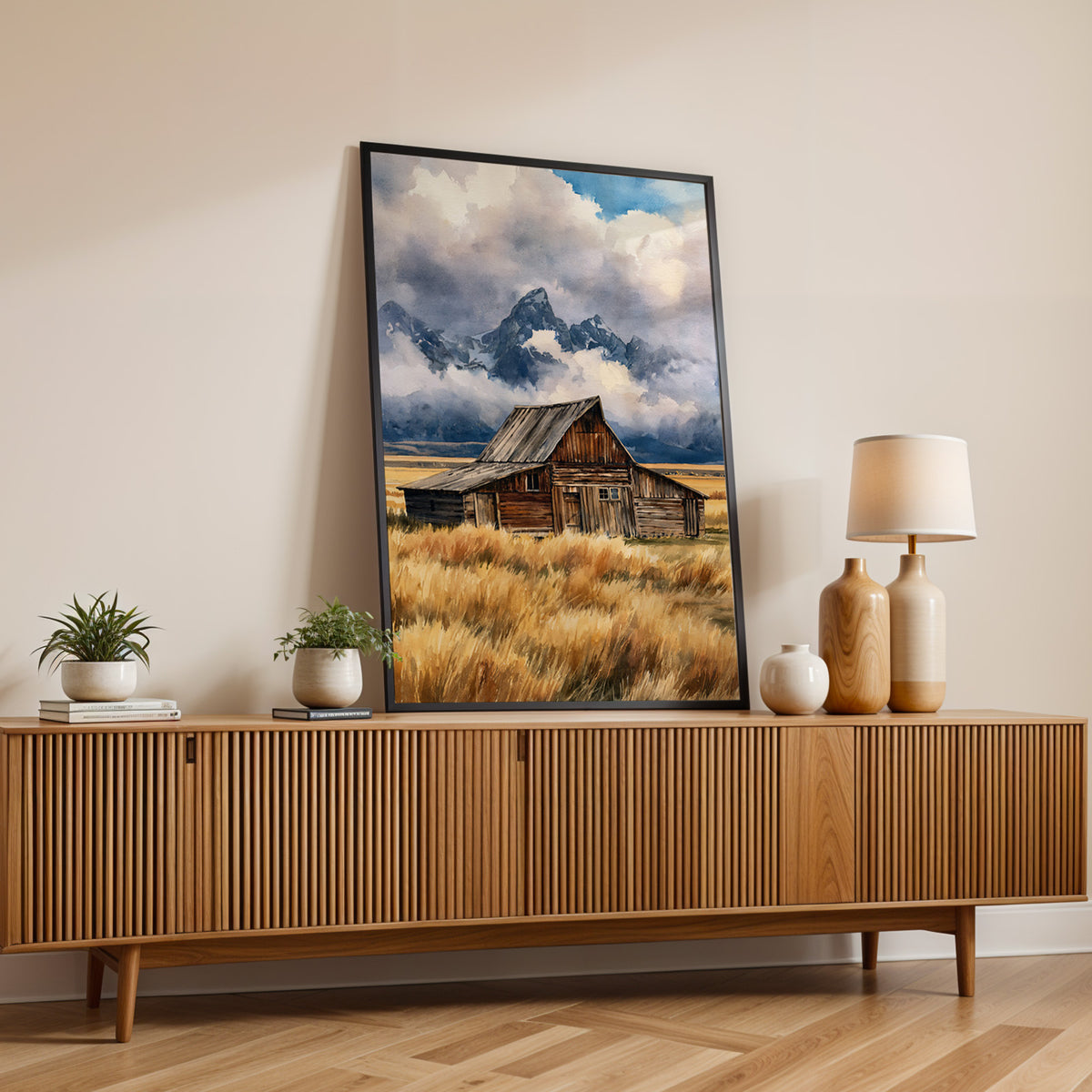 Grand Teton National Park watercolor print in a black frame on a fluted wood sideboard with a lamp and small plants