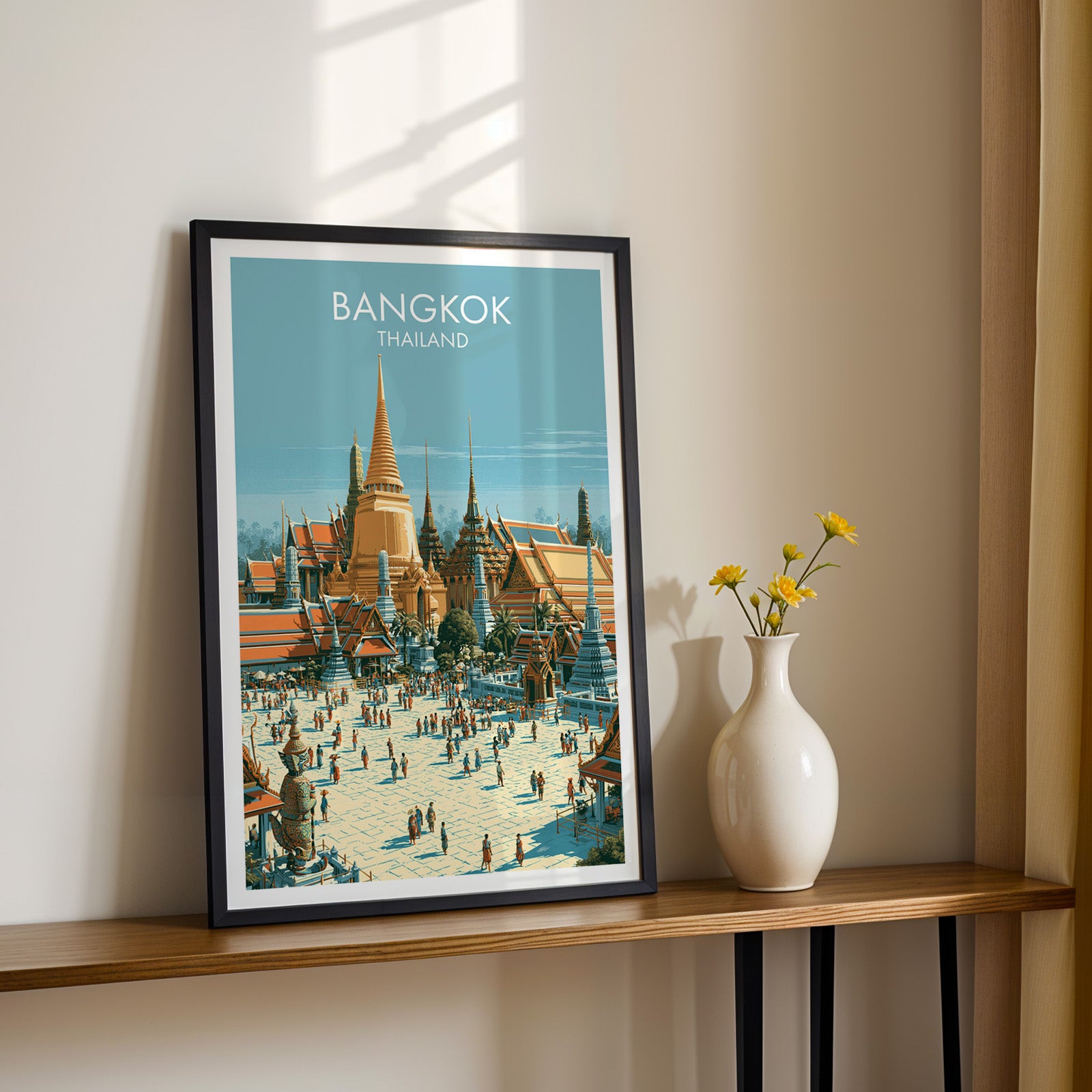 Black framed Grand Palace Bangkok Thailand print on a narrow hallway console in sunlight, styled with yellow flowers