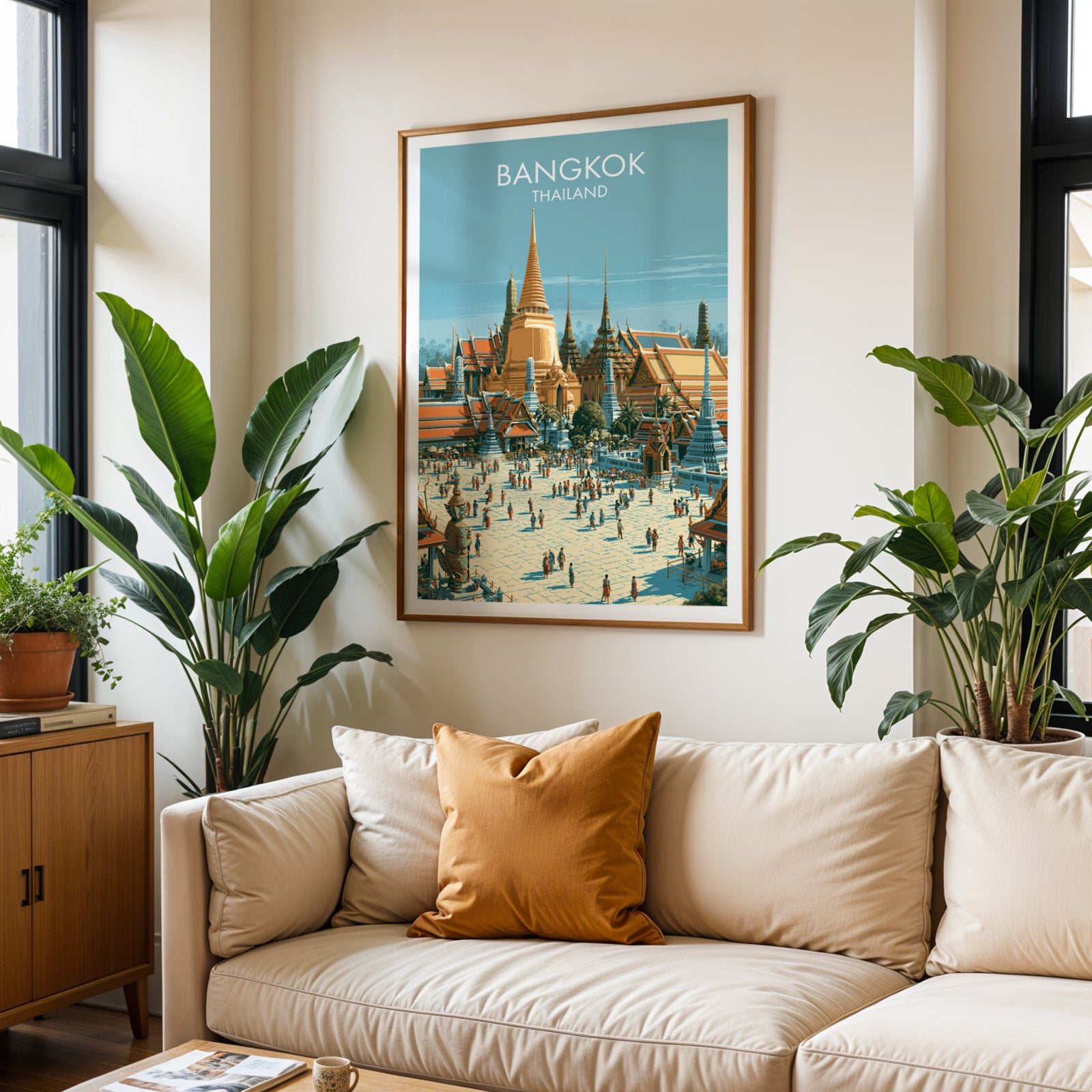 Framed Grand Palace Bangkok Thailand wall art hanging above a cream sofa in a bright living room with tropical plants