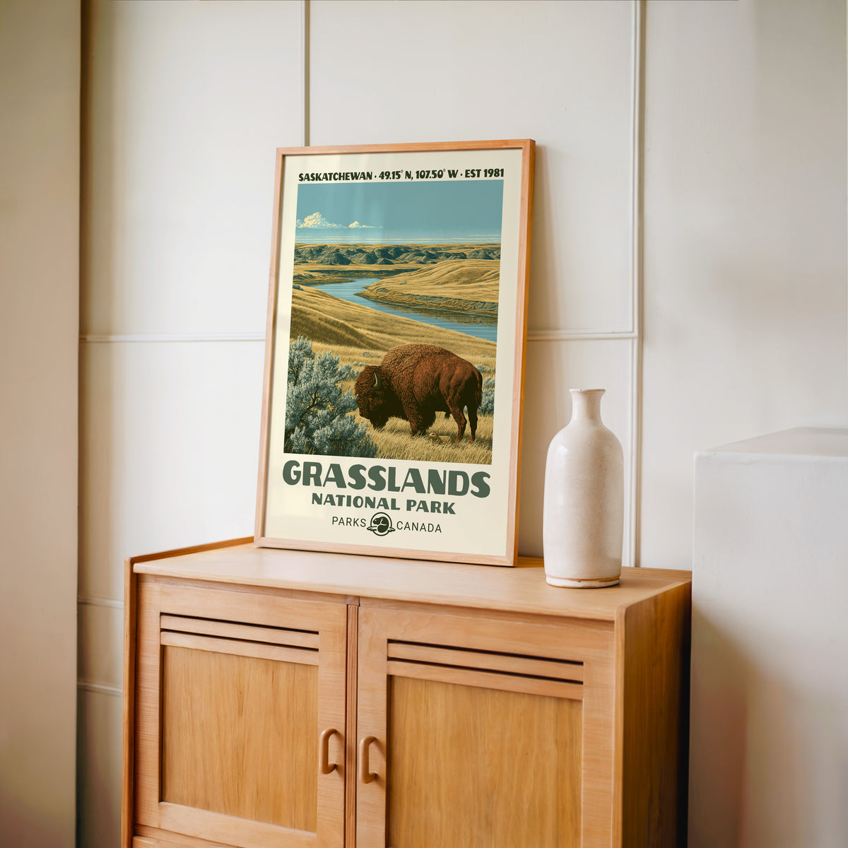 Saskatchewan badlands valley wall art in an oak frame on a wood cabinet beside a stoneware vase
