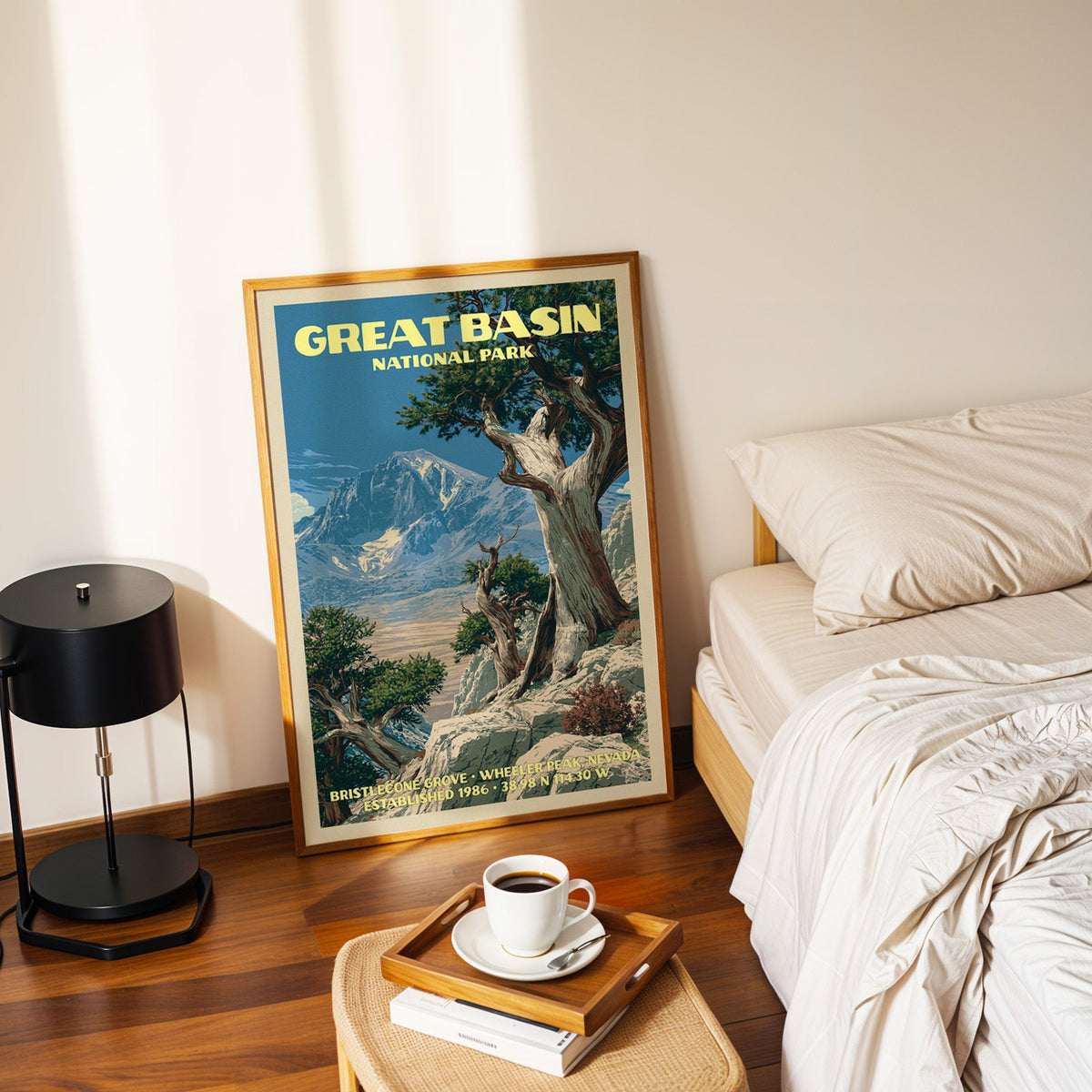 Bristlecone Grove poster in a gold frame on the bedroom floor beside a made bed and a black table lamp