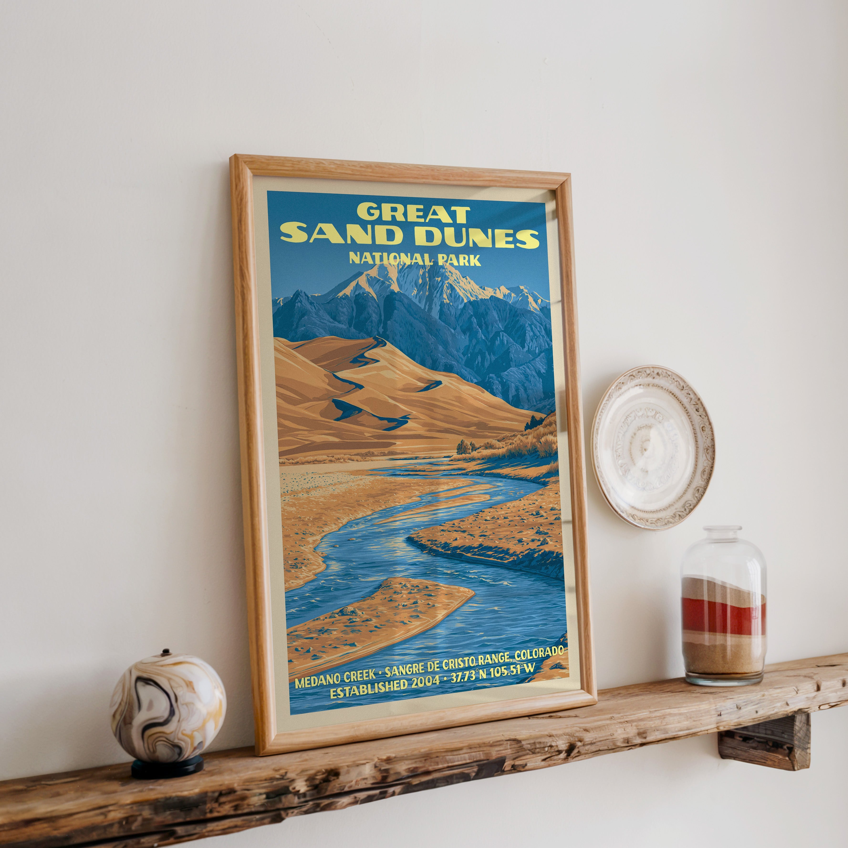 Great Sand Dunes print in oak, leaning on a reclaimed wood ledge with a marbled stone sphere and a sand jar
