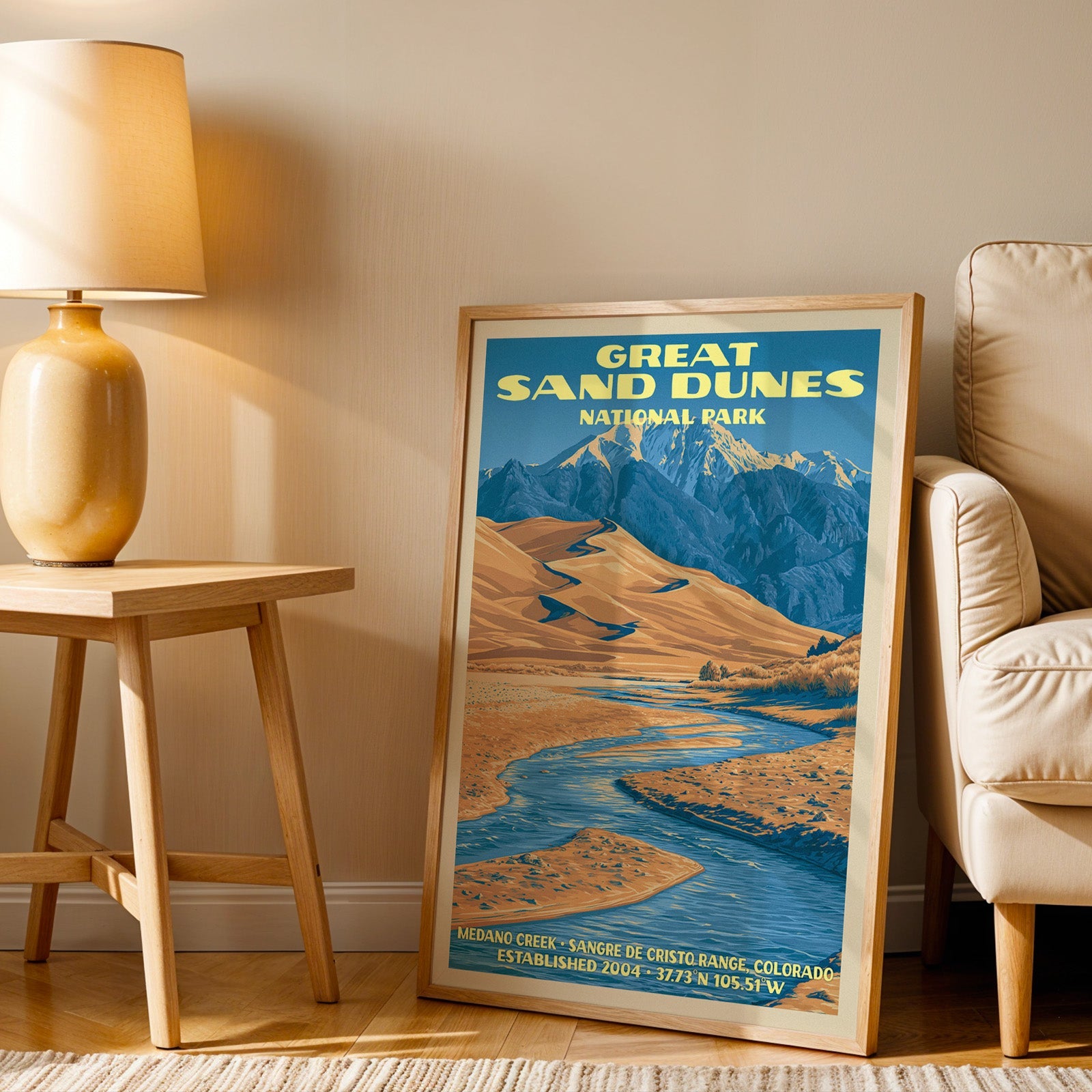 Sangre de Cristo dunes wall art in oak, leaning by a cream armchair and a side table with an ochre lamp