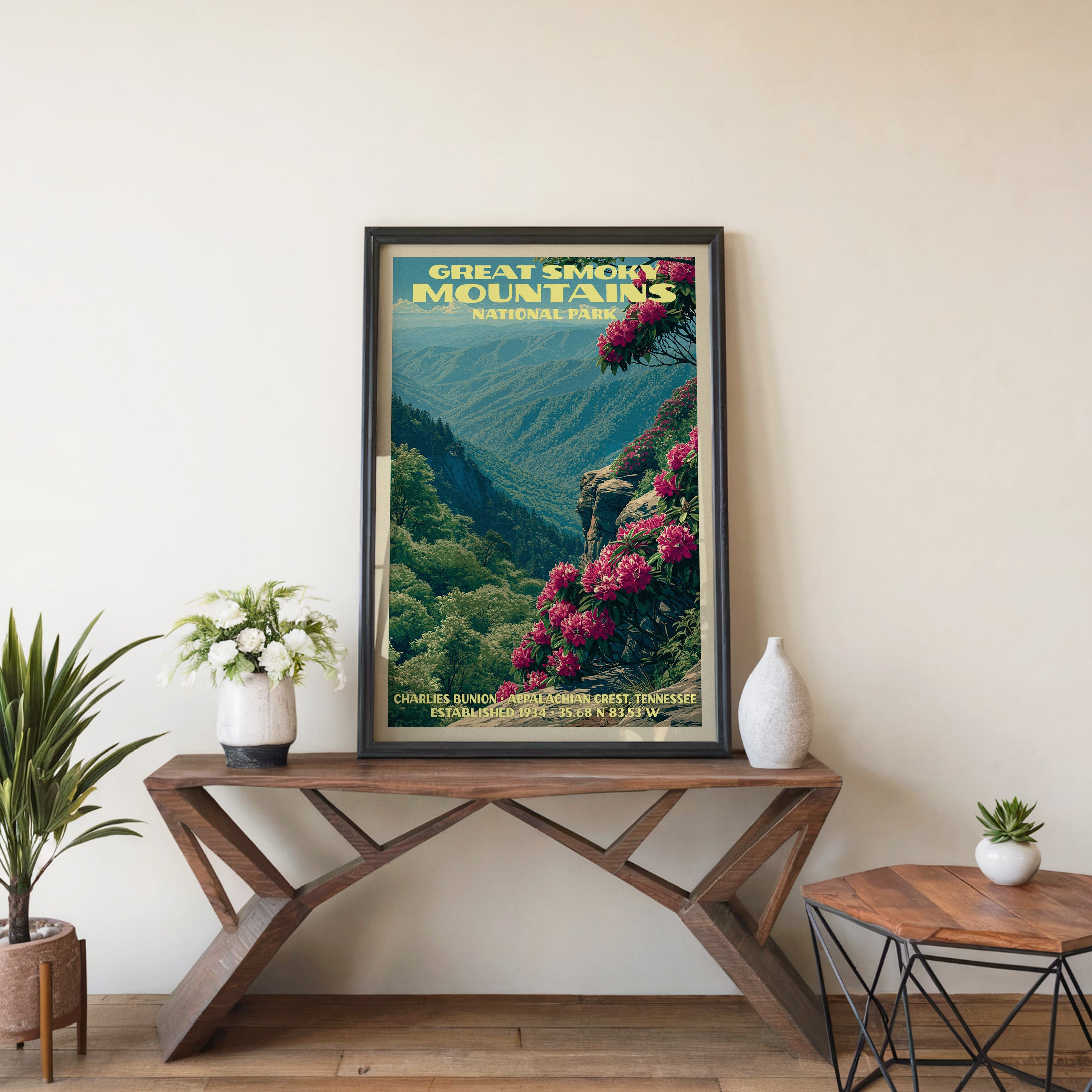 Charlies Bunion wall art in a black frame, leaning on a walnut console with white anemones in a stoneware vase