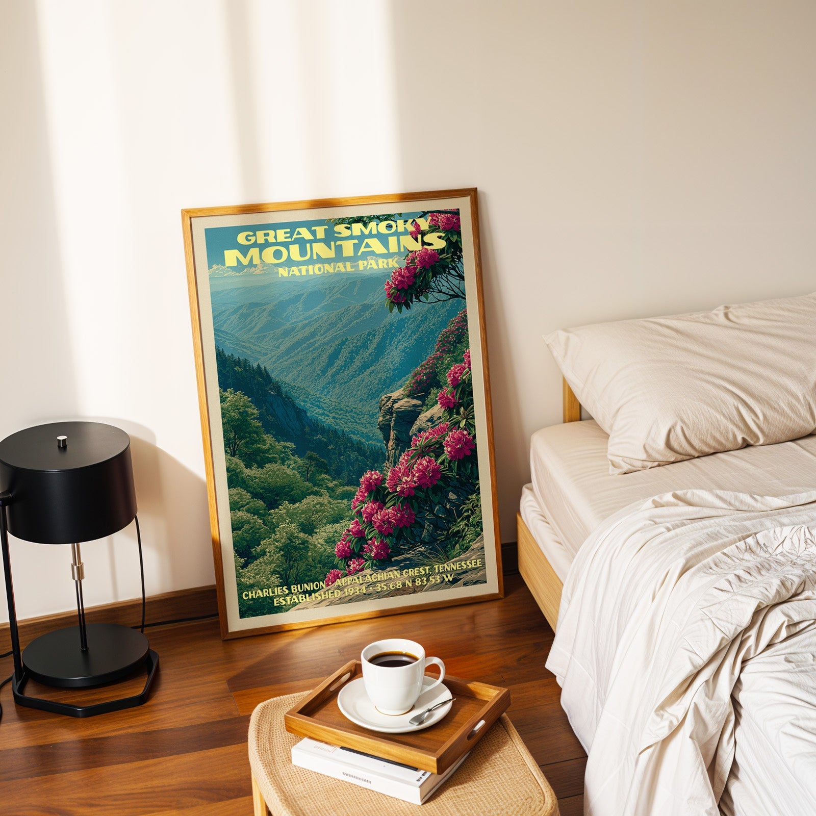 Charlies Bunion rhododendron poster in a gold frame on the bedroom floor beside a made bed and a black table lamp