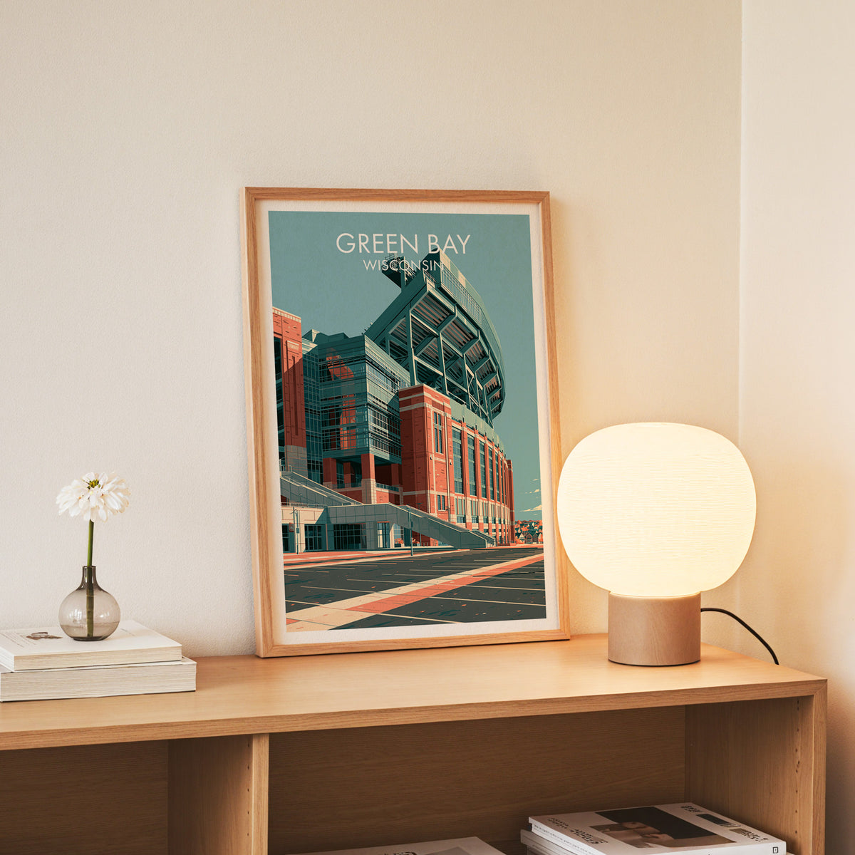 Green Bay canvas print in a slim oak frame on a console beside daisies in a glass jar